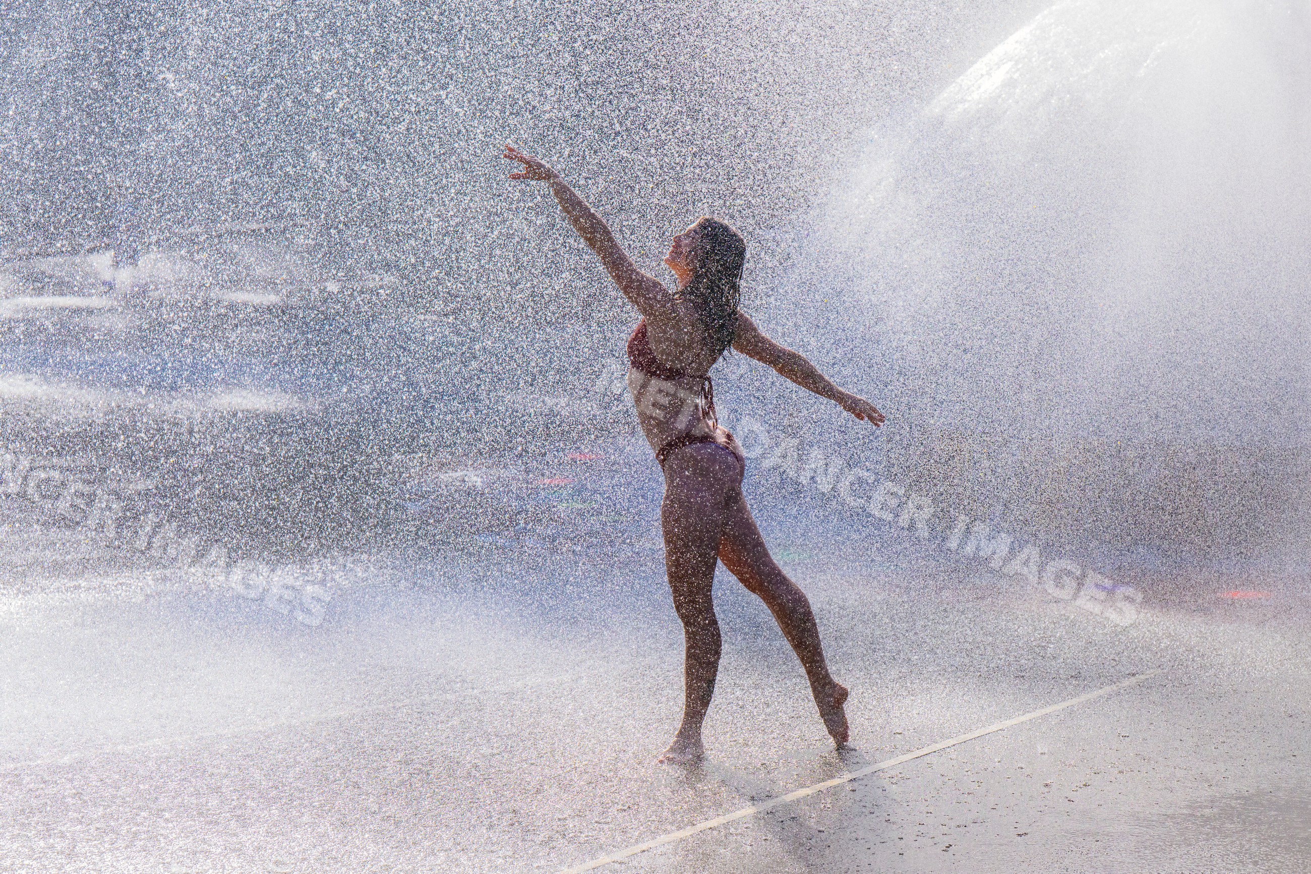 White woman dancing in water spray outdoors