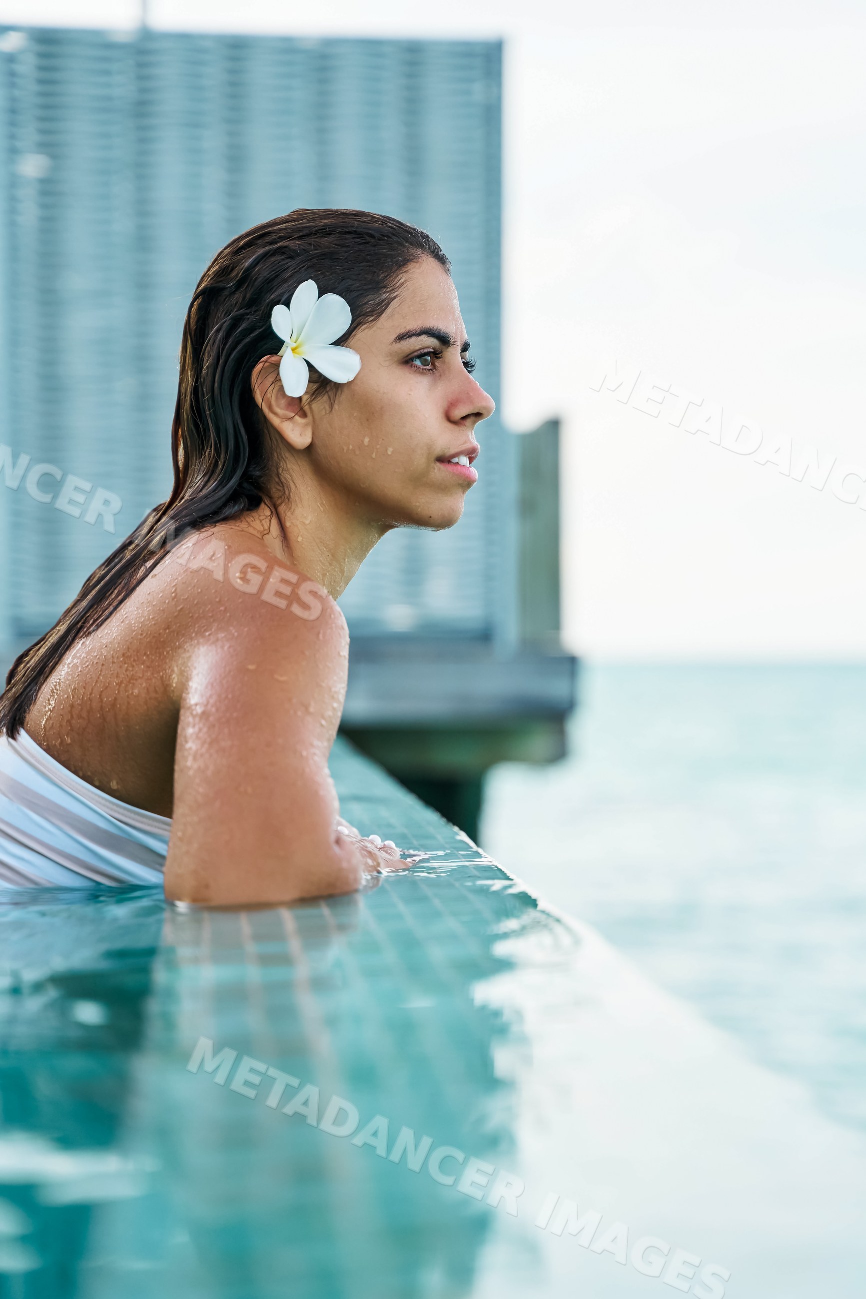 A white woman relaxes in a pool with ocean view
