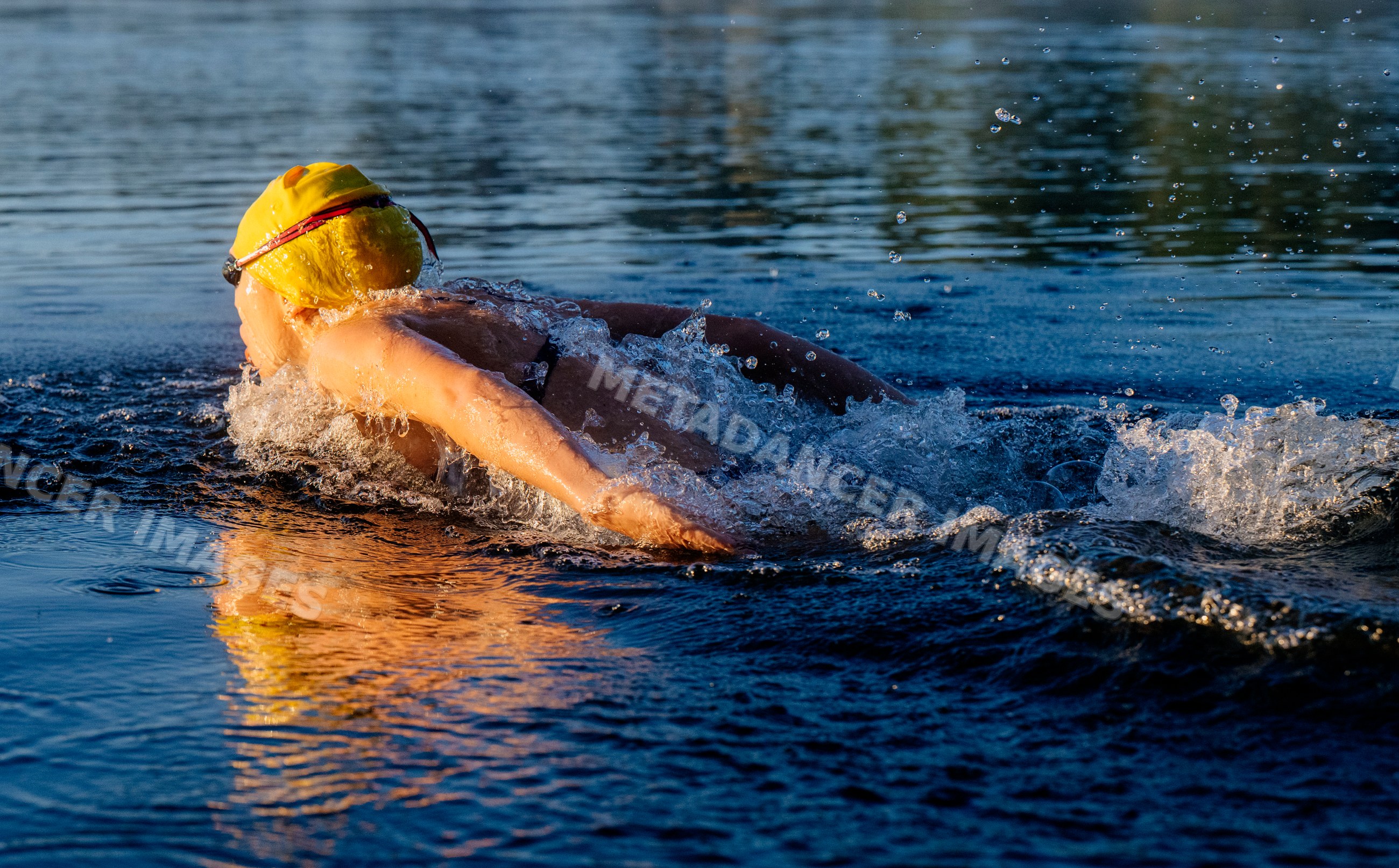 White swimmer in yellow cap swimming in open water in USA