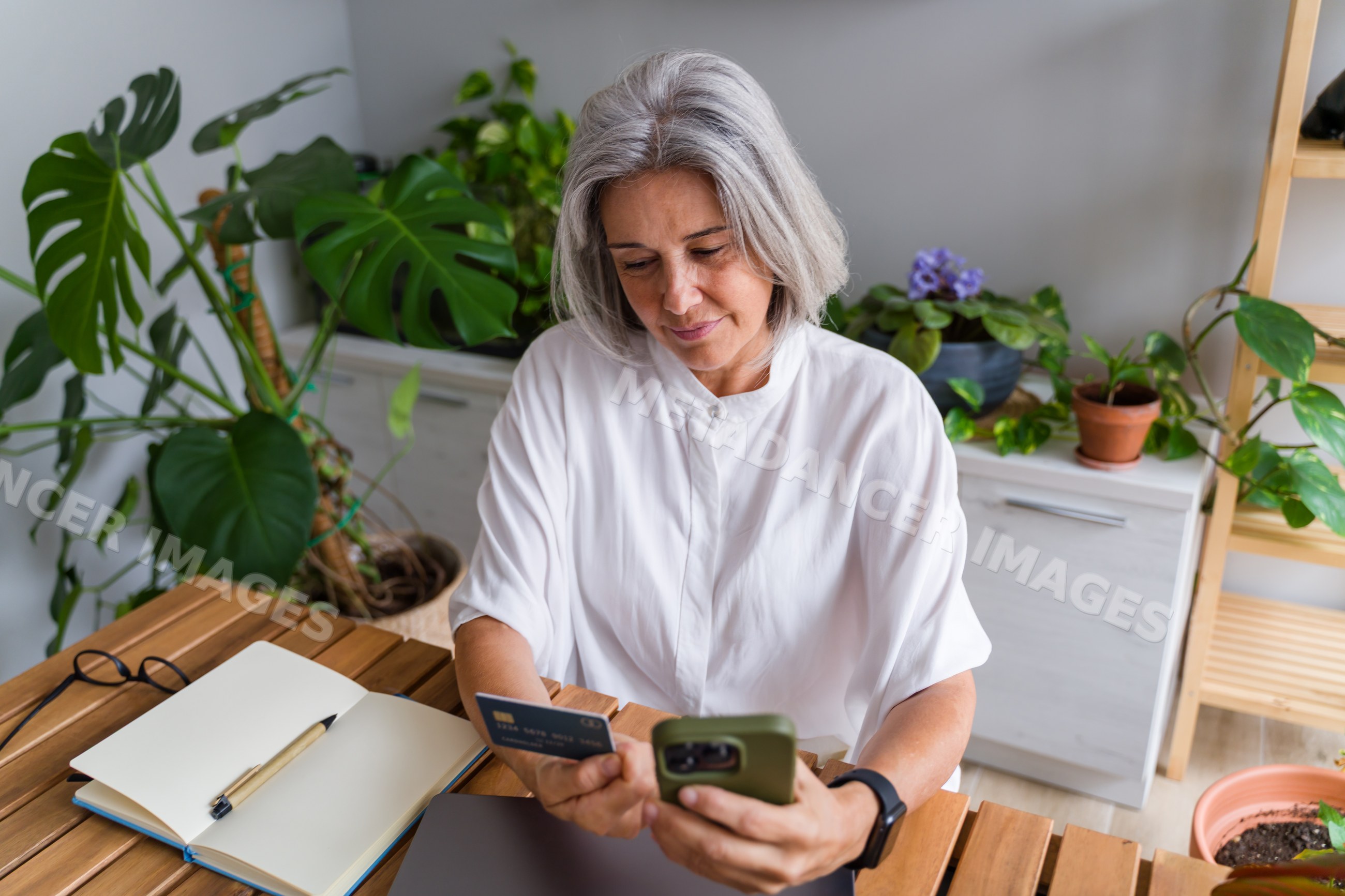 Older white woman using credit card and smartphone for online shopping