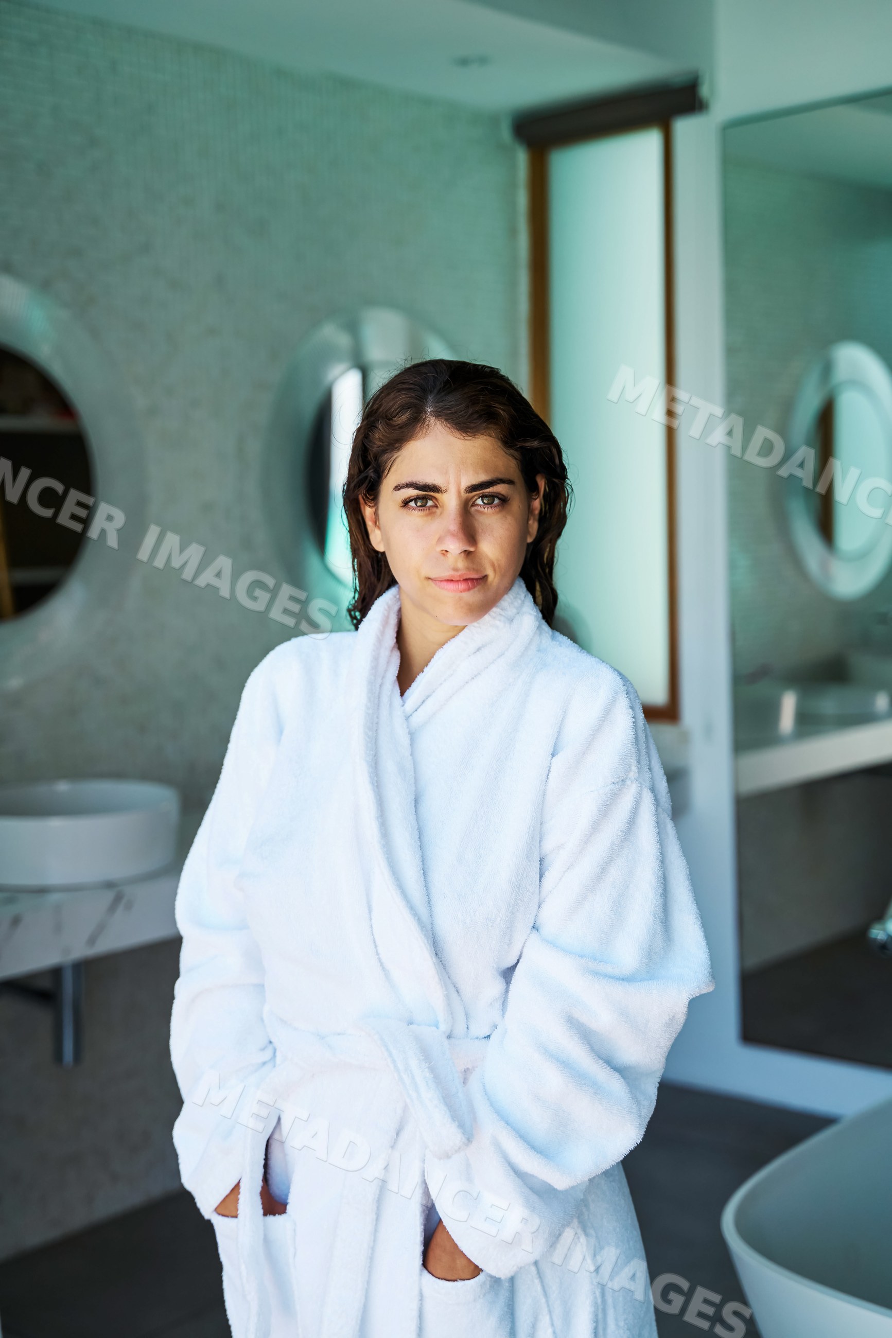 A woman in a white bathrobe stands in a modern bathroom