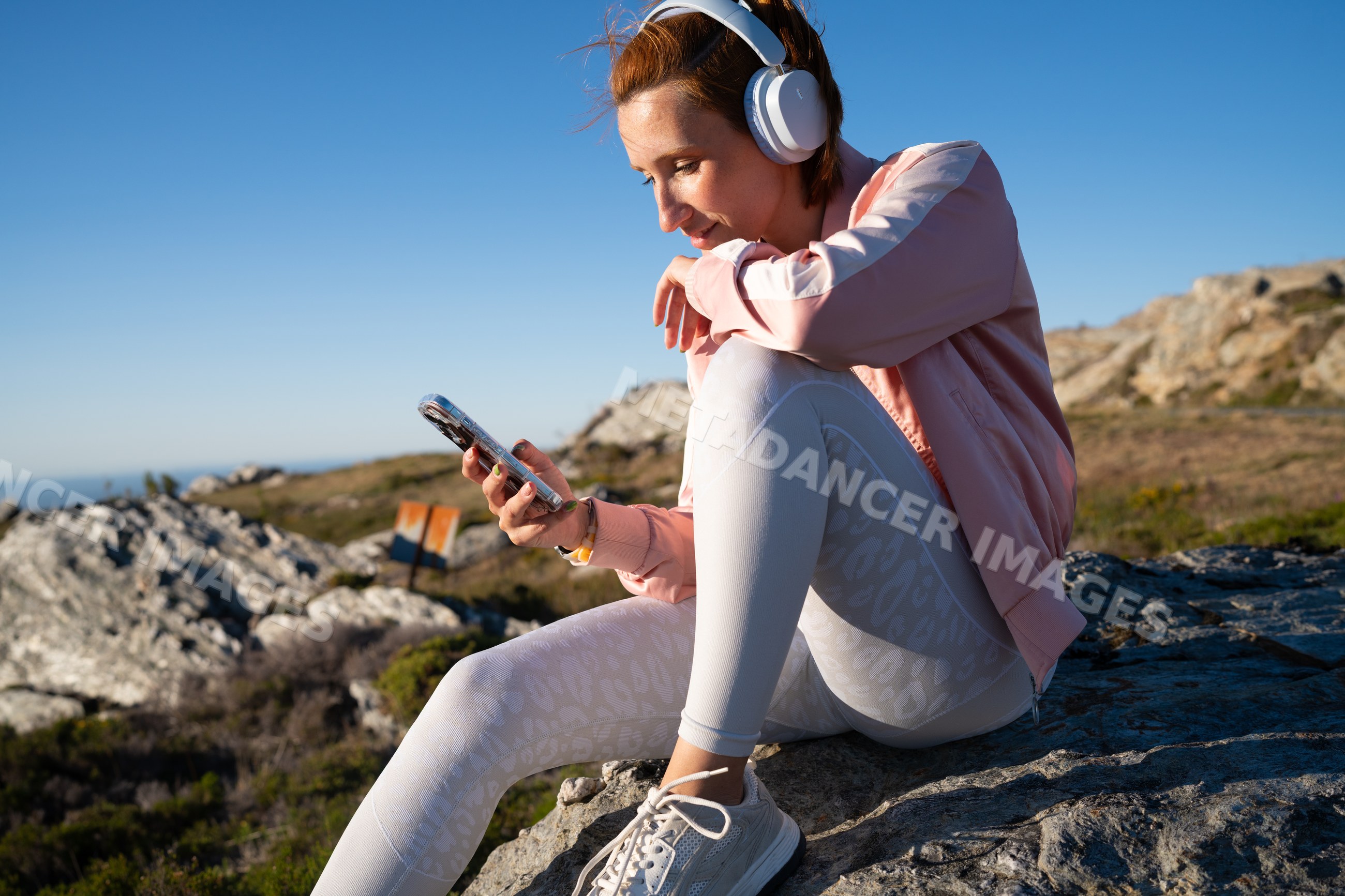White Woman wearing headphones using smartphone