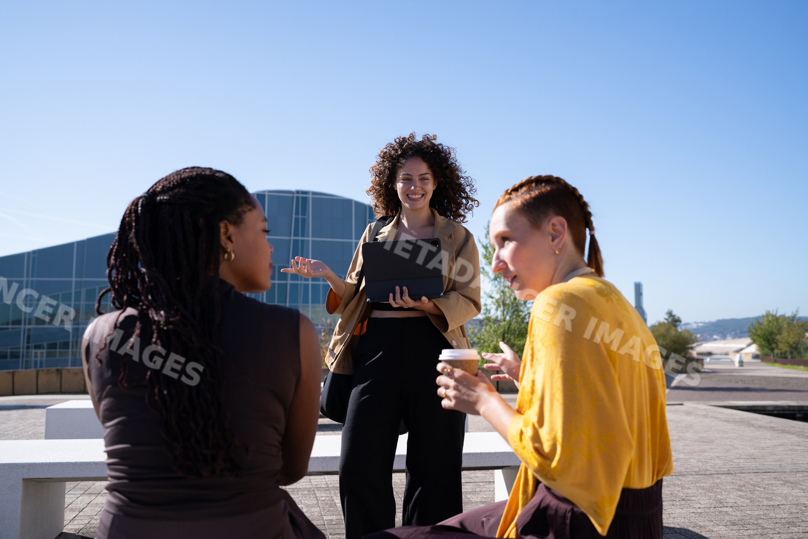 African American and white women having outdoor meeting with tablet