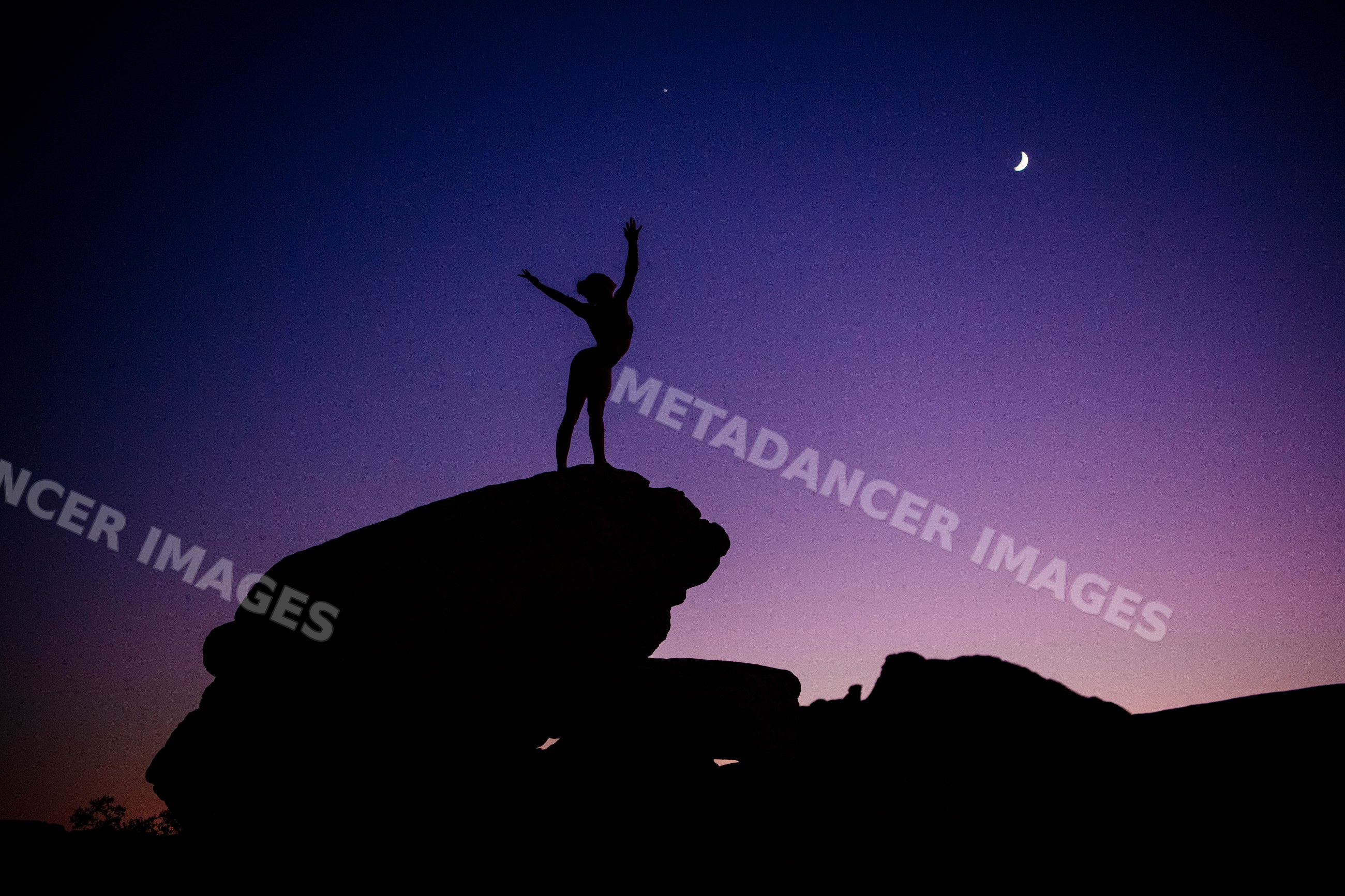 Silhouette of white person practicing yoga on rock