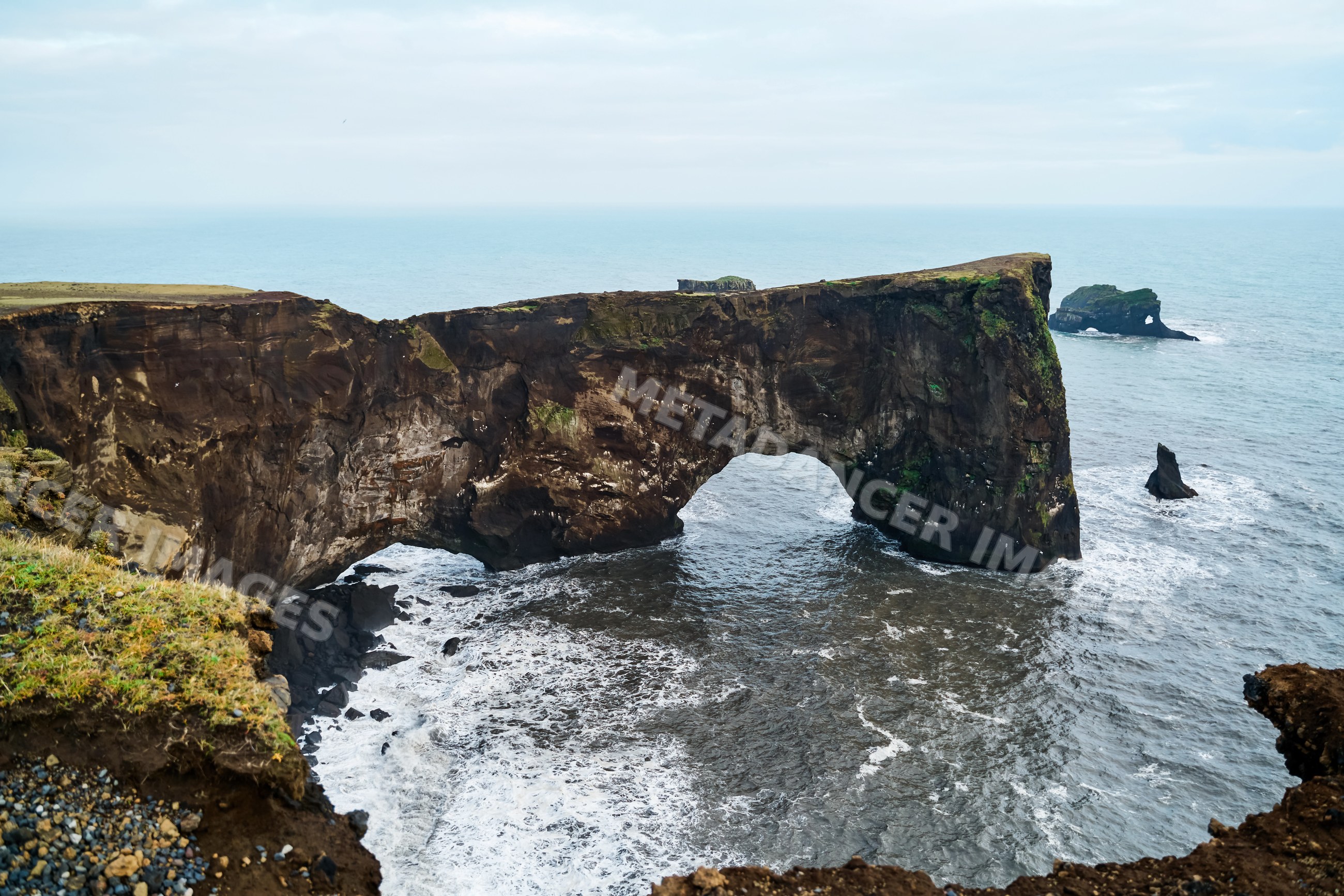 Natural rock arch stands over ocean waves along Iceland's rugged