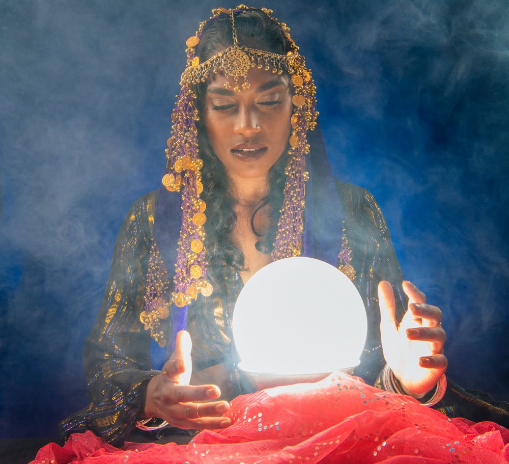 A South Asian woman holding a glowing crystal ball for fortune telling