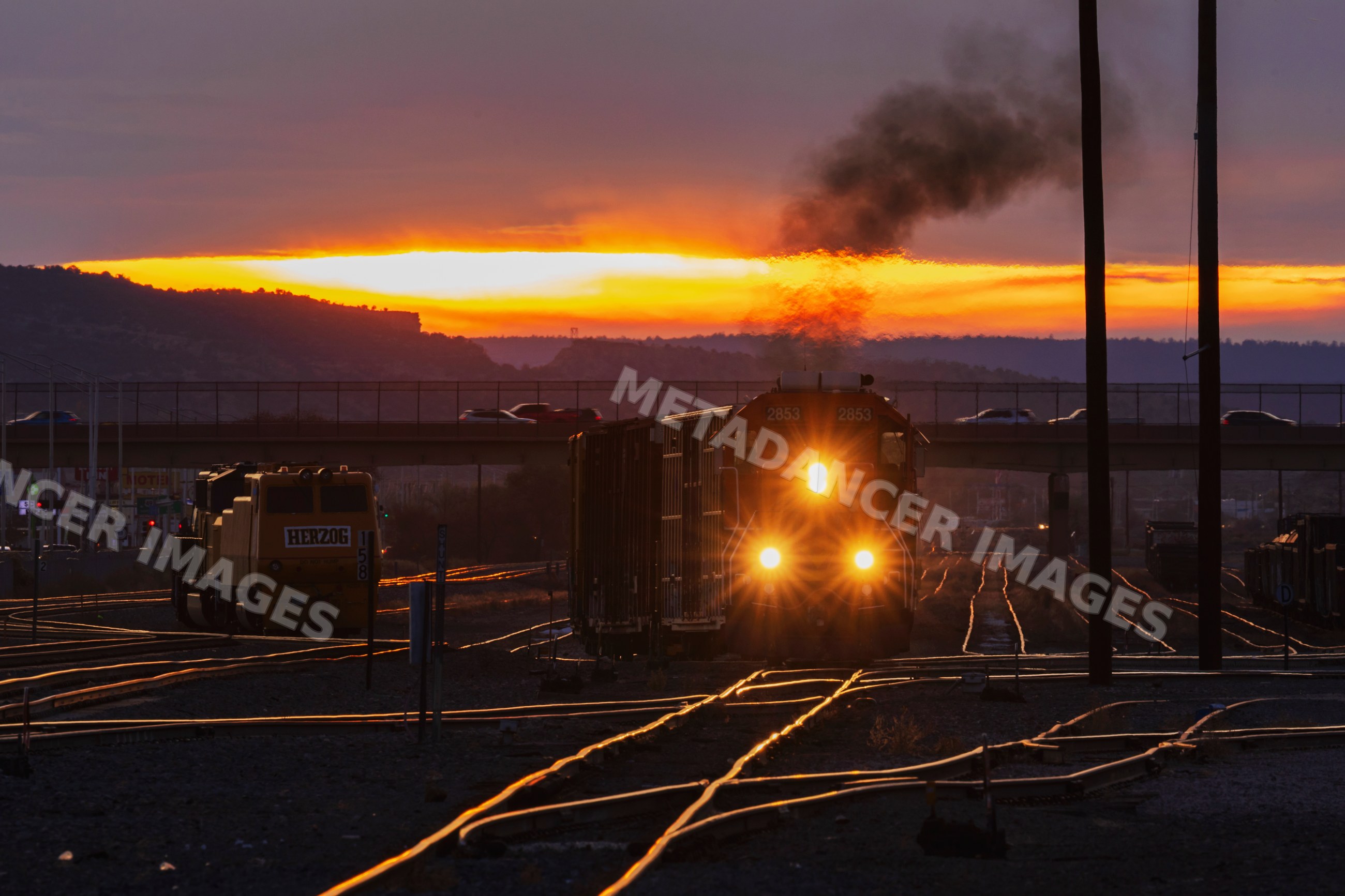 Train approaching railway switch yard at sunset in gallup, new mexico