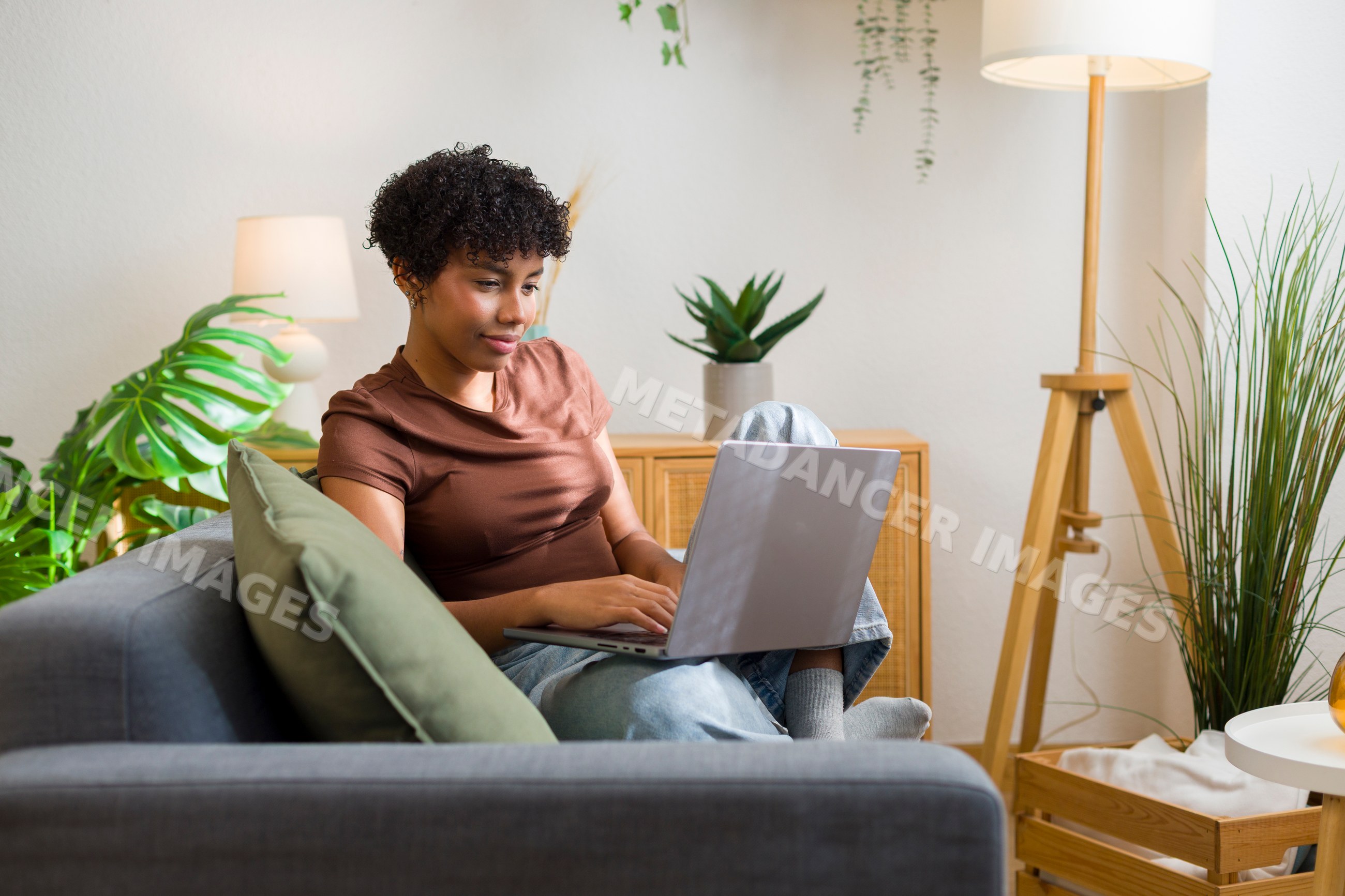 Young African American woman using laptop on sofa