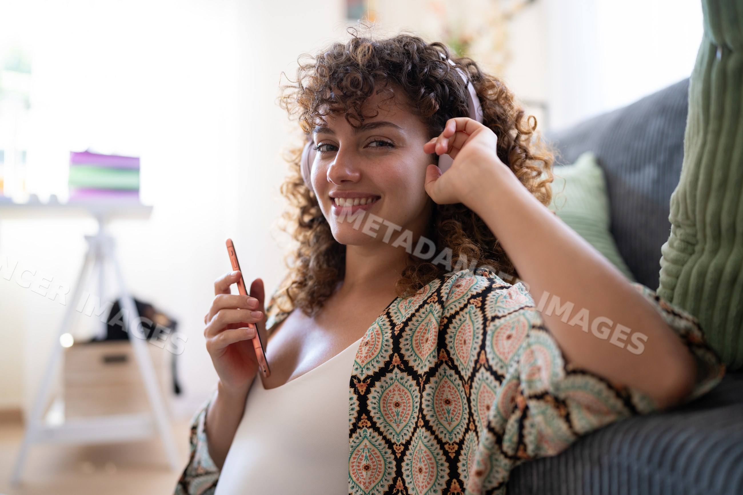 White woman with headphones enjoying music at home on couch