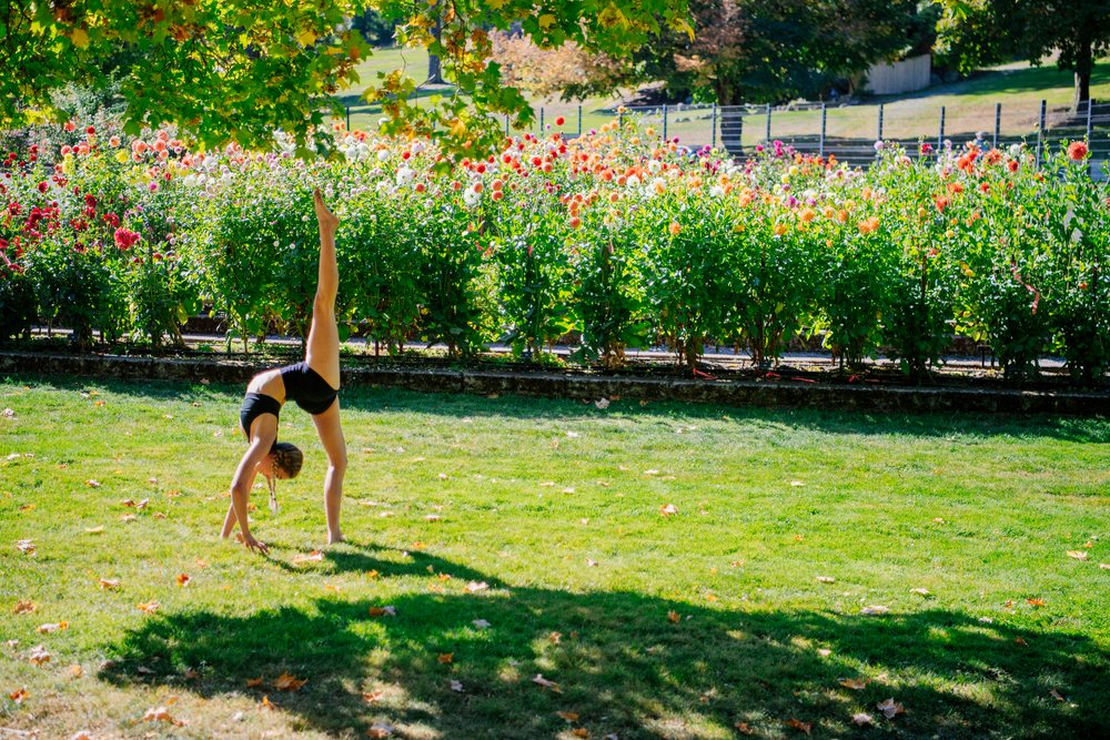 Contortionist performing yoga pose in sunny garden with flowers