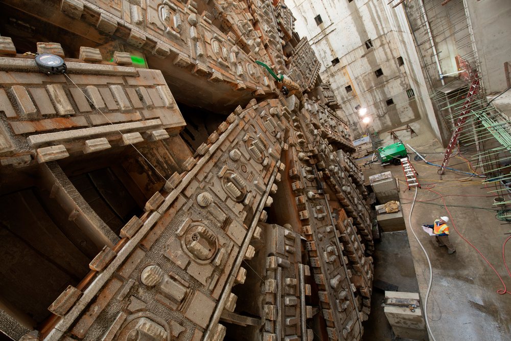 White construction workers inspect a tunnel boring machine