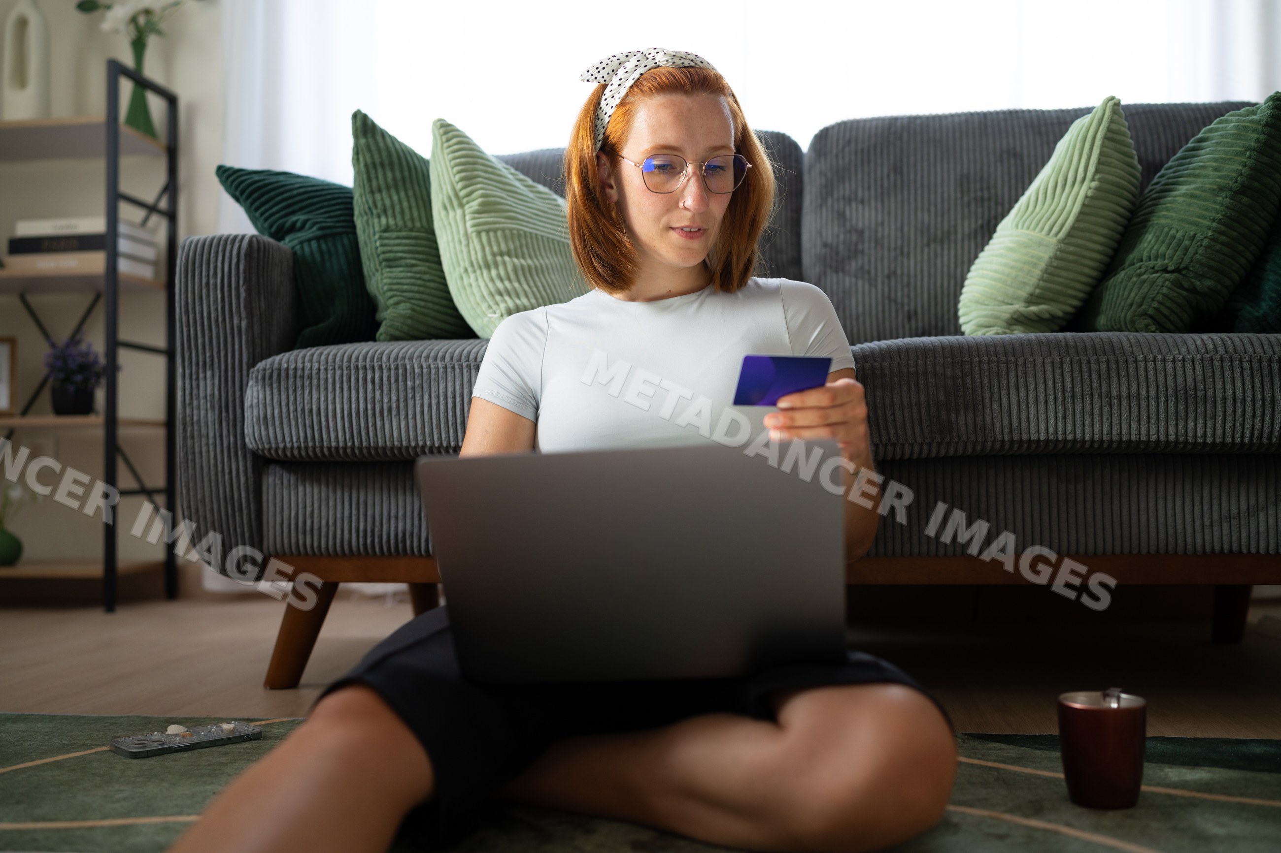 A white woman uses a laptop and credit card for online shopping