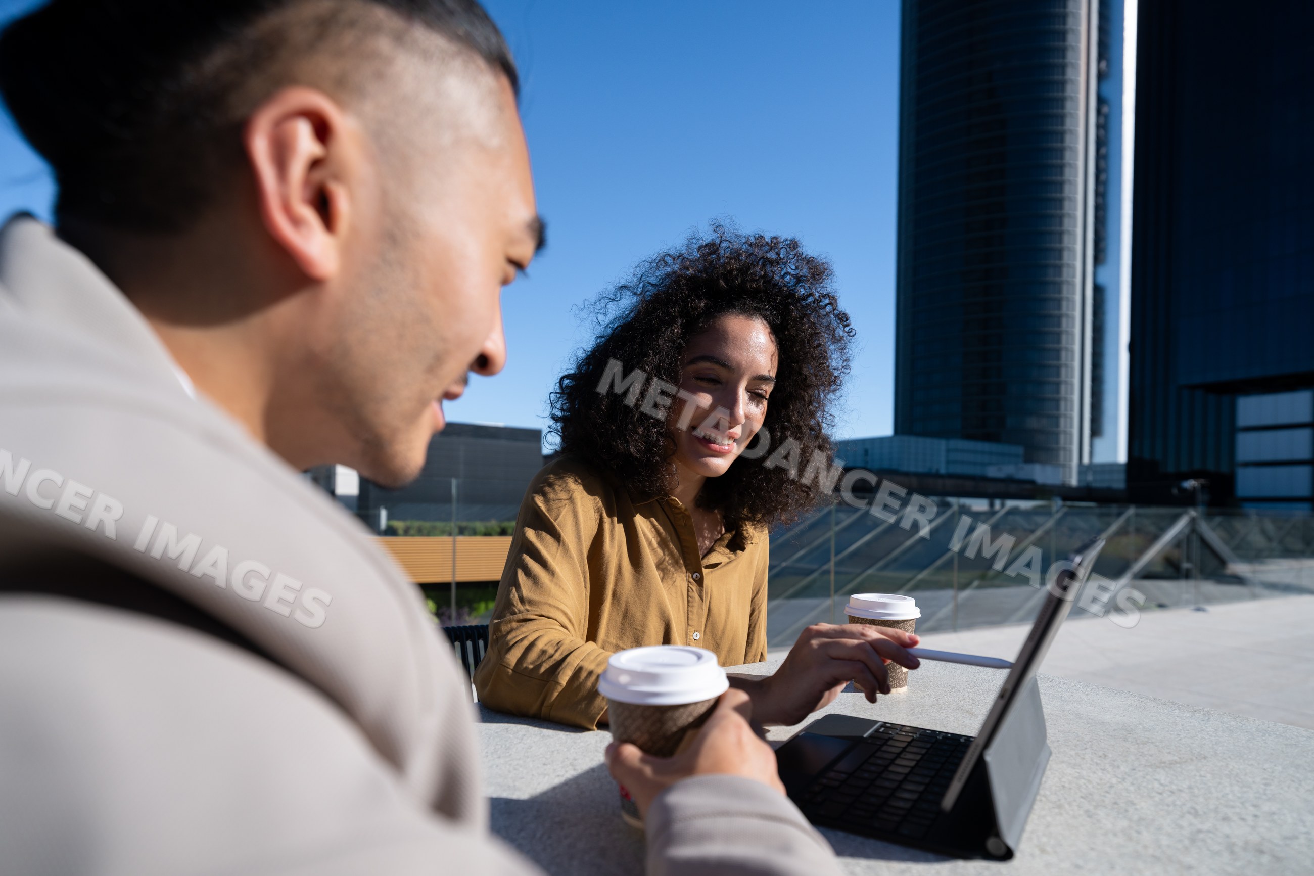 Two people having business meeting with coffee and laptop outdoors