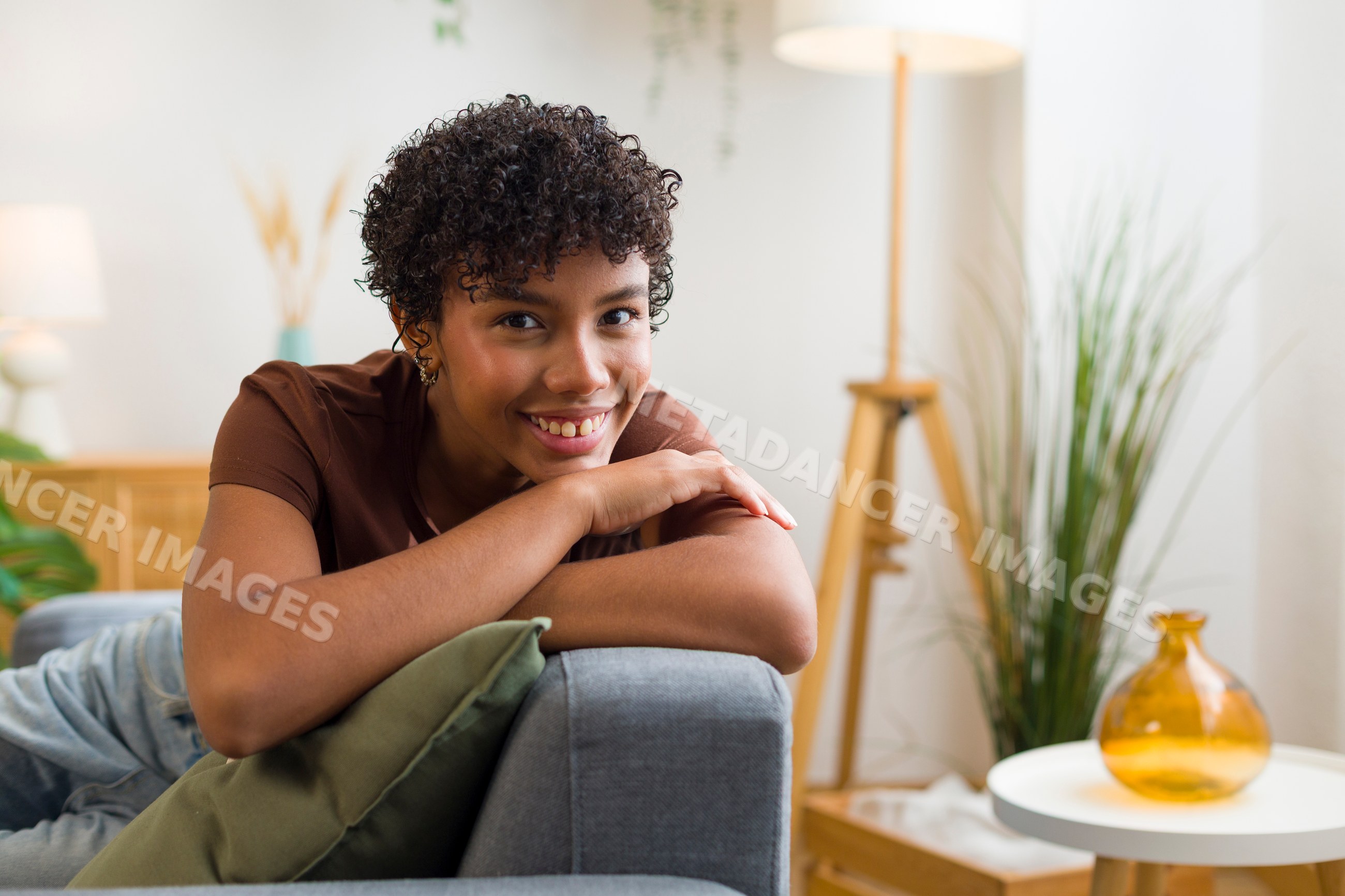 Young African American woman resting on couch in cozy home interior