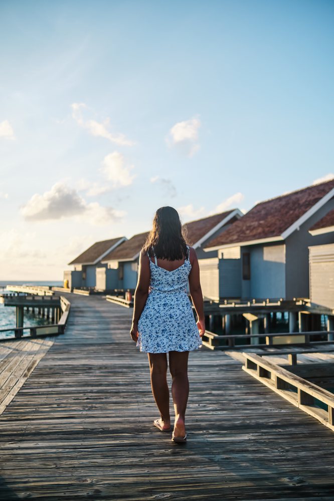 White Woman walking on a wooden pier with overwater bungalows