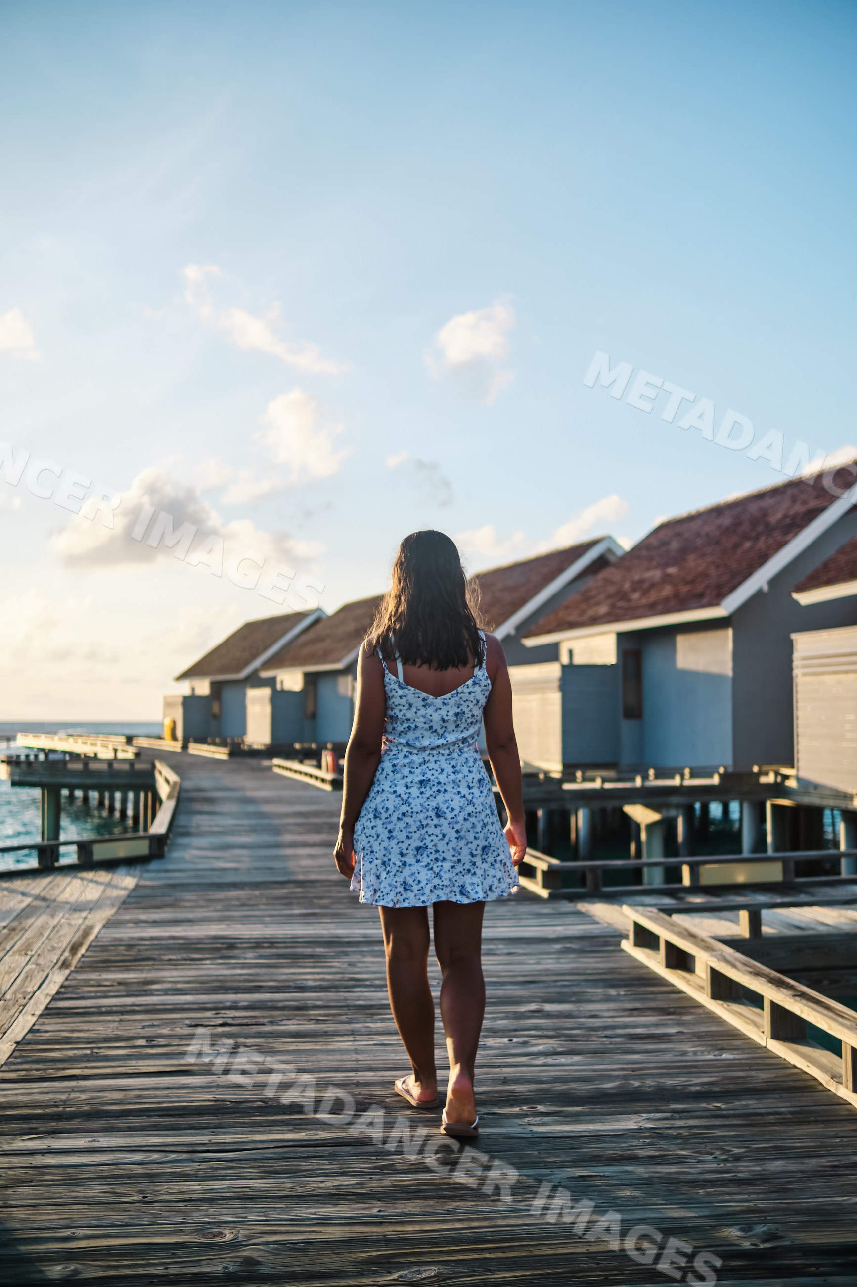 White Woman walking on a wooden pier with overwater bungalows