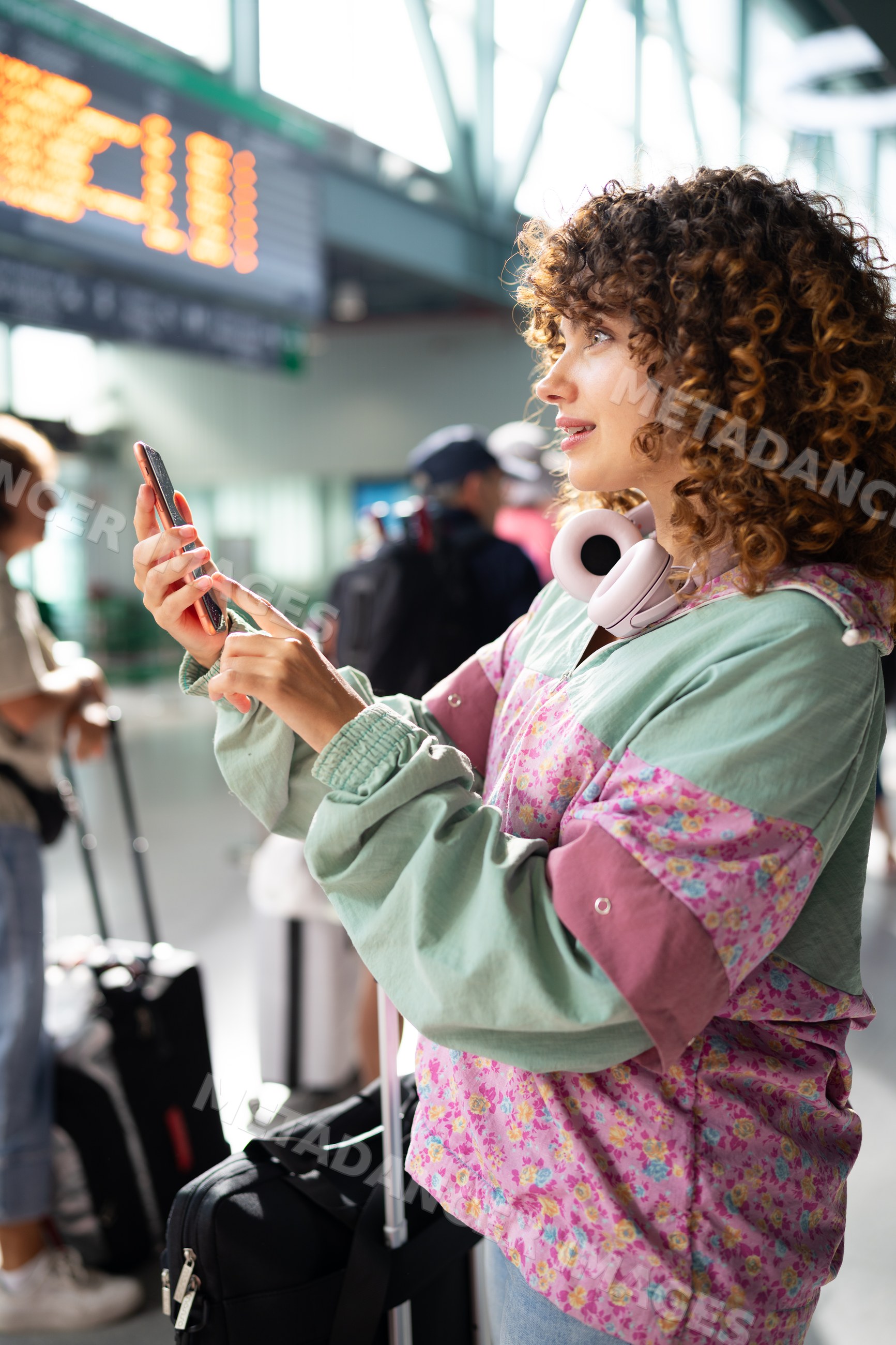 White woman checking phone with luggage in airport terminal