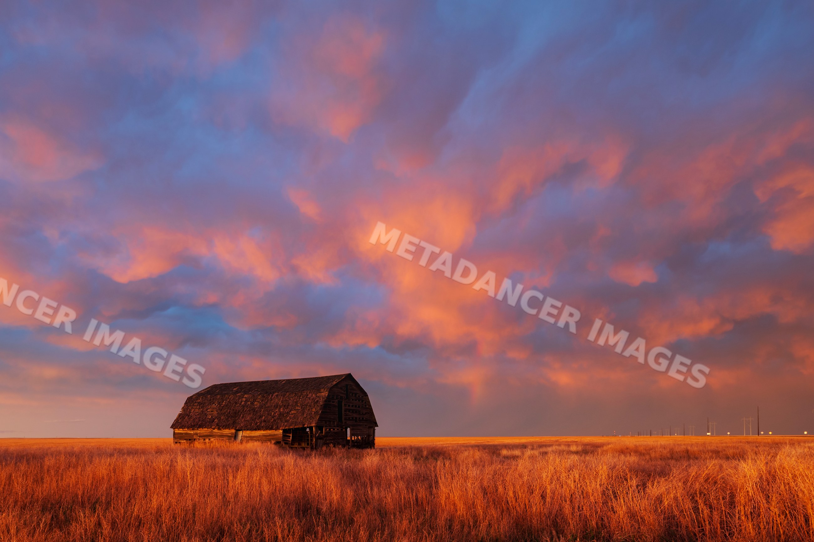 Old barn with dramatic Sunset clouds in oklahoma grassland
