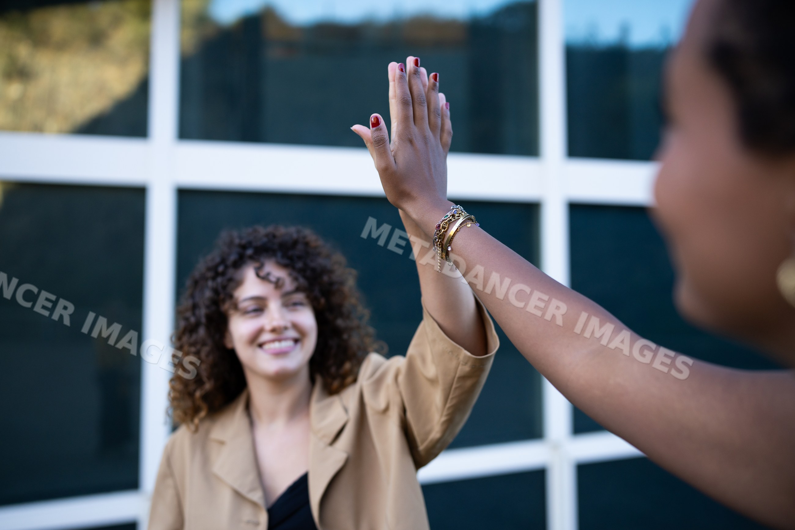 African American and white women sharing a high five outdoors