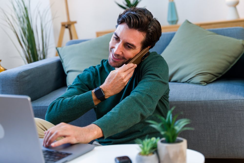 White man multitasking with laptop and phone
