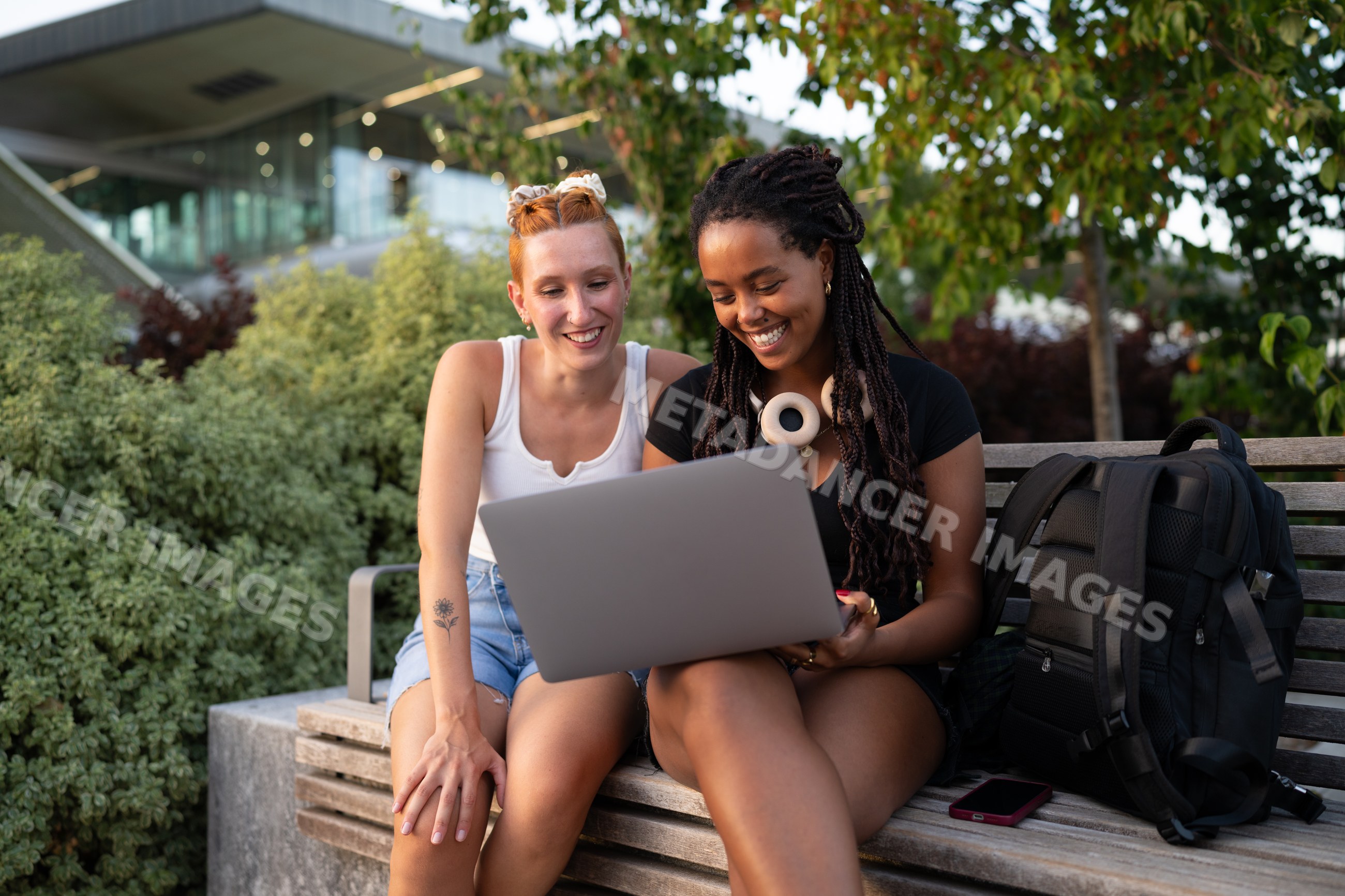 Two young white and African American women using a laptop together
