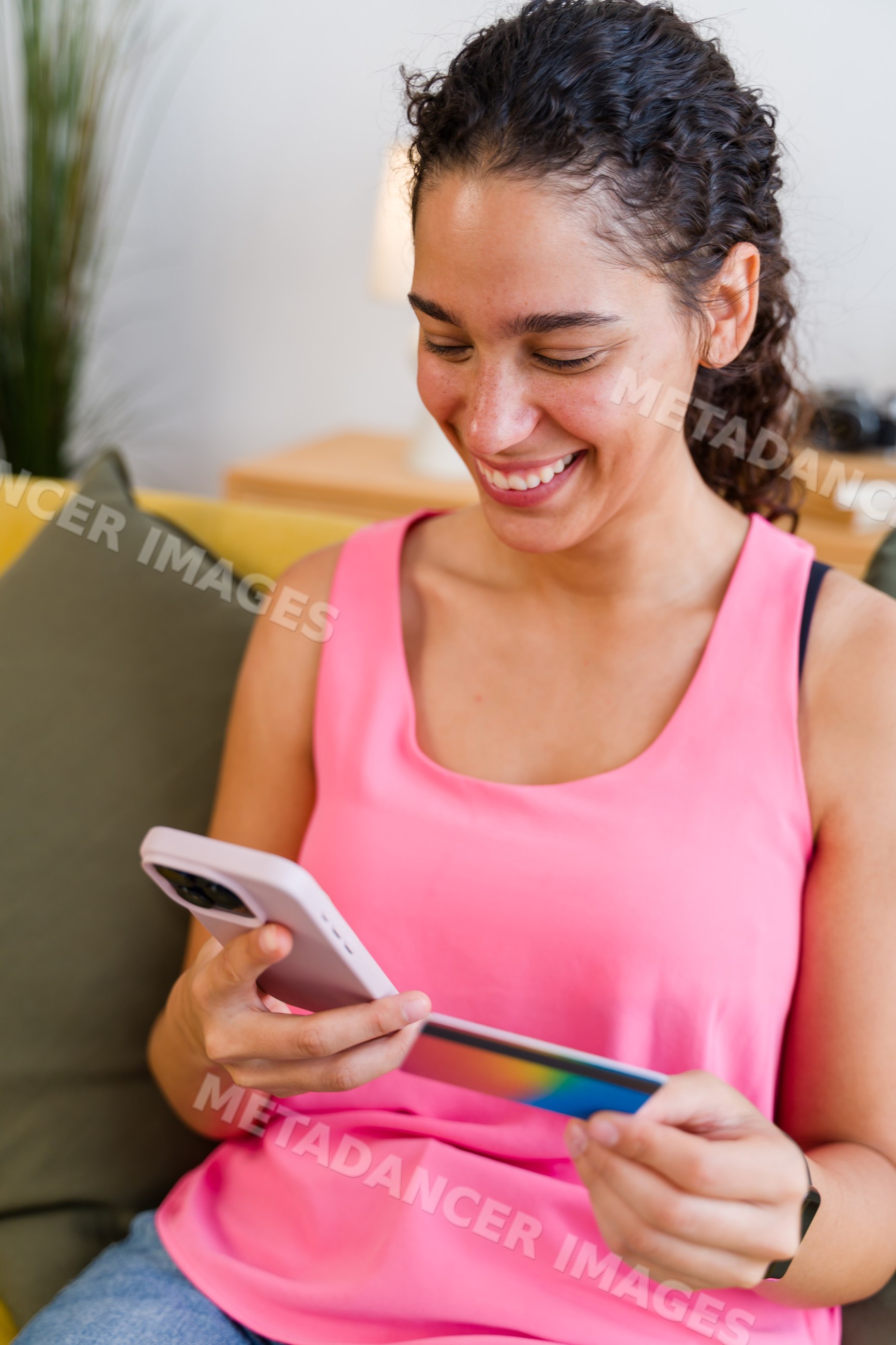 A Hispanic woman uses a smartphone and payment card for online