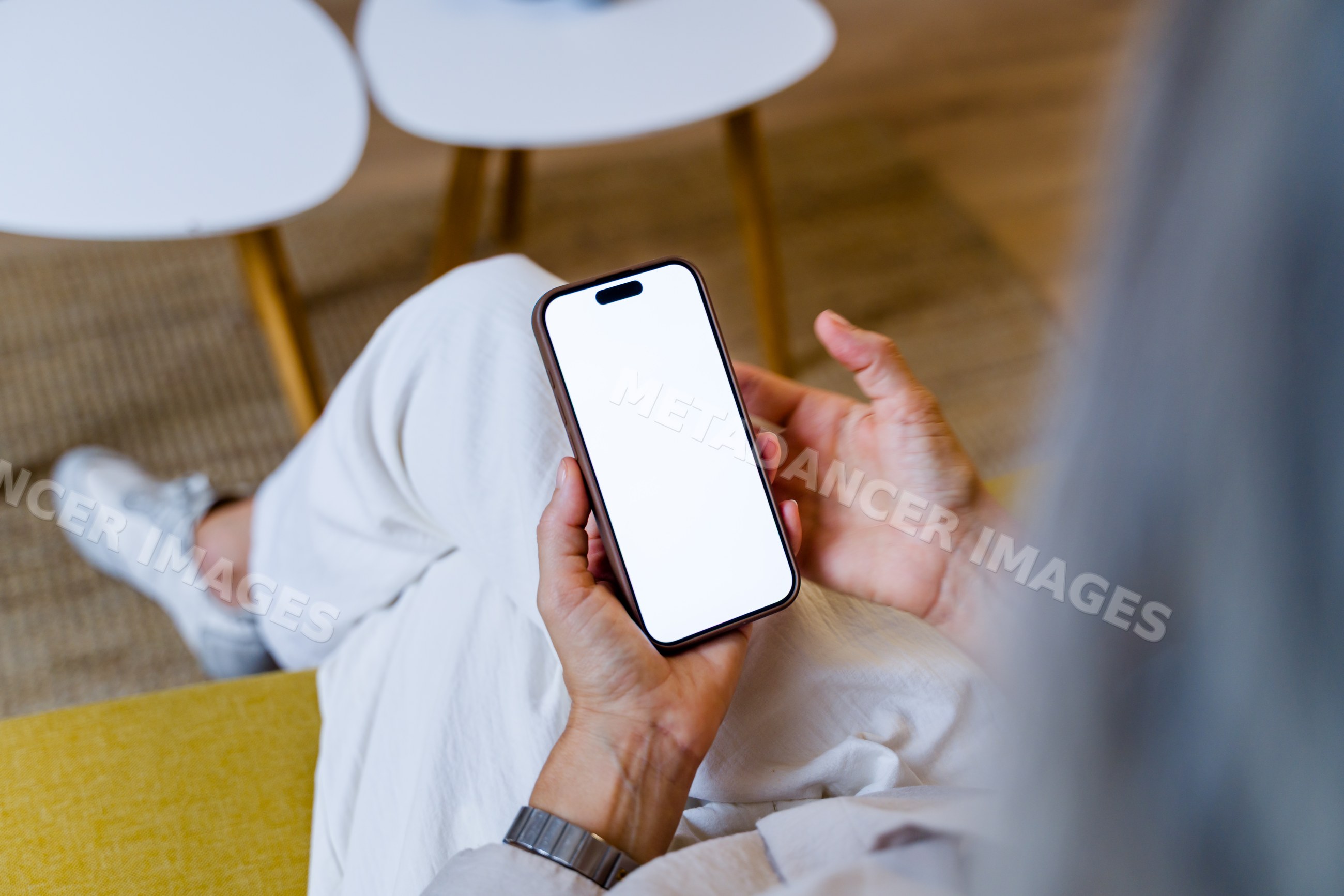 Person holding smartphone with blank white screen indoors