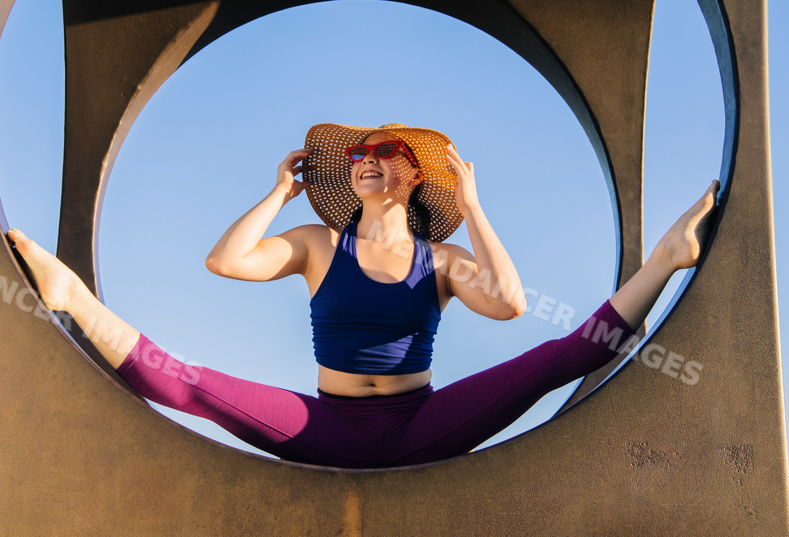 White woman stretching in a split pose outdoors in a circular frame