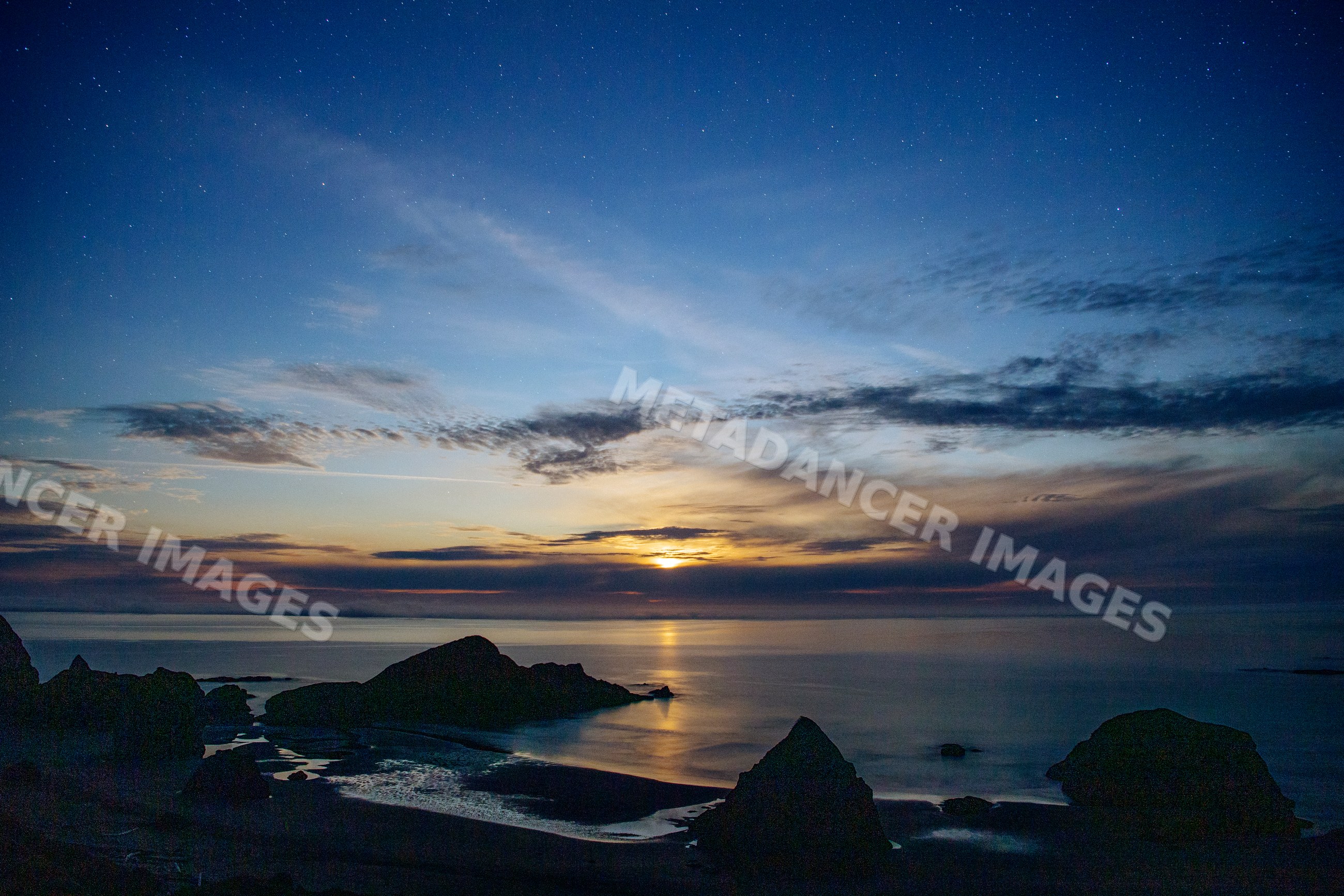 Night sky with stars over rocky coastline at twilight in Oregon