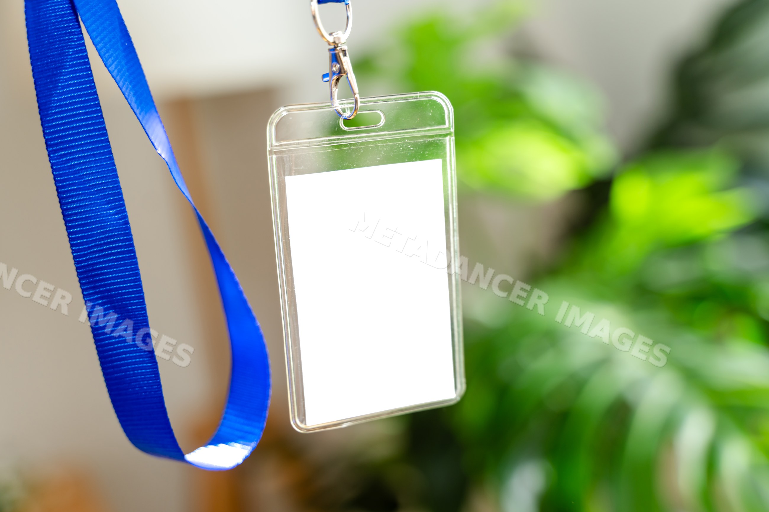 Blank plastic badge holder with blue lanyard hanging with blurred