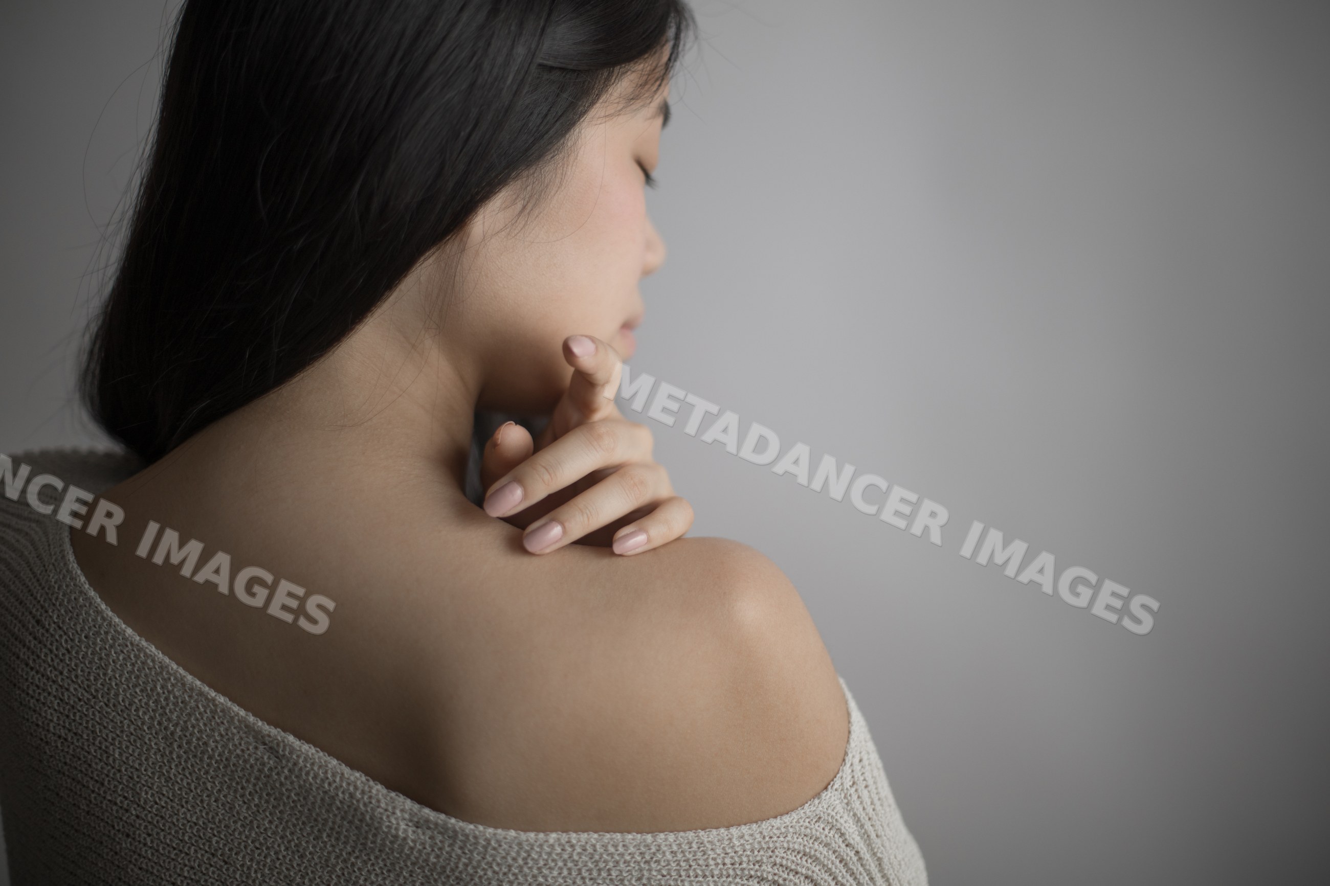 Southeast Asian woman touching shoulder in a thoughtful, peaceful pose