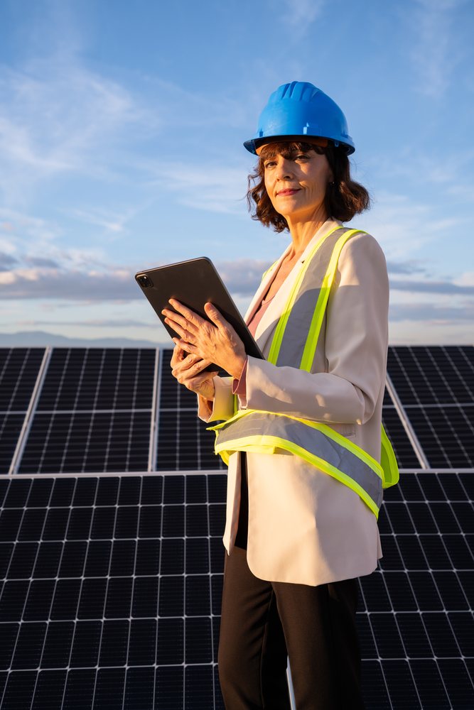 White woman engineer with tablet at solar panel installation