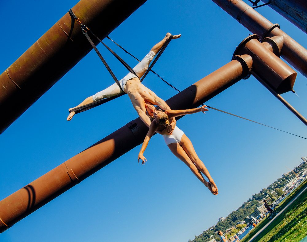 Aerialists performing acrobatic aerial silk routine on iron pipes