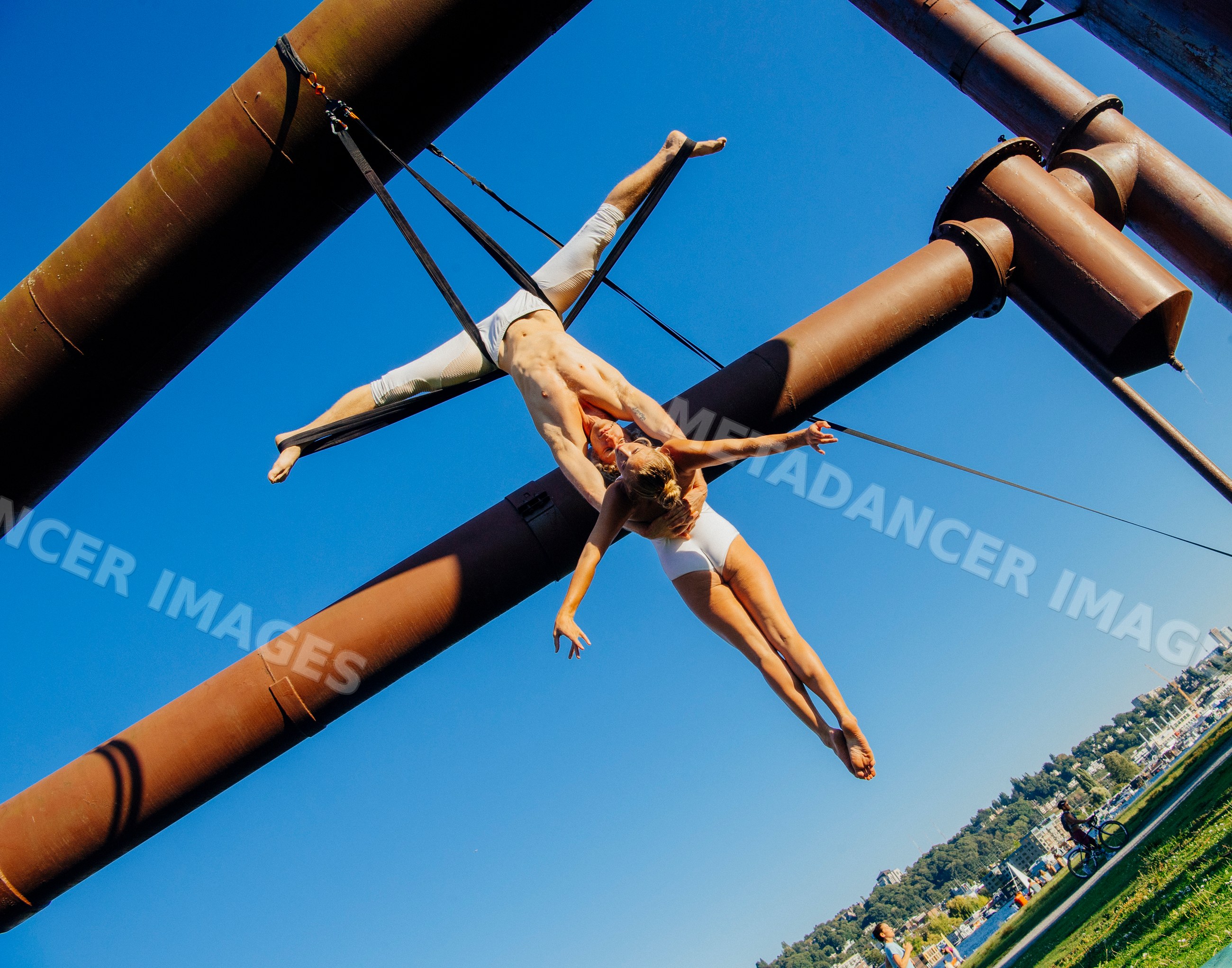 Aerialists performing acrobatic aerial silk routine on iron pipes