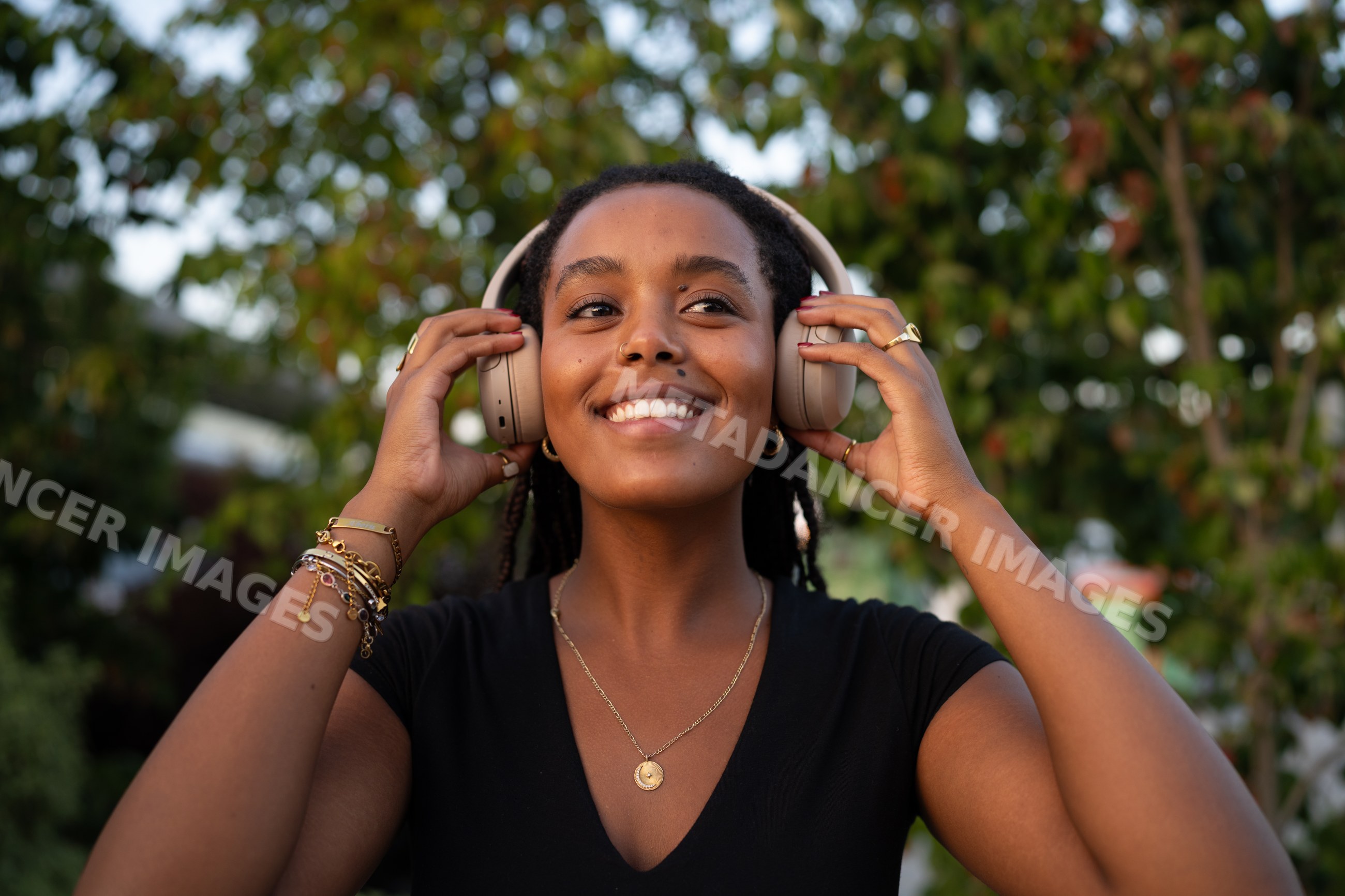 A smiling African American woman adjusts wireless audio device