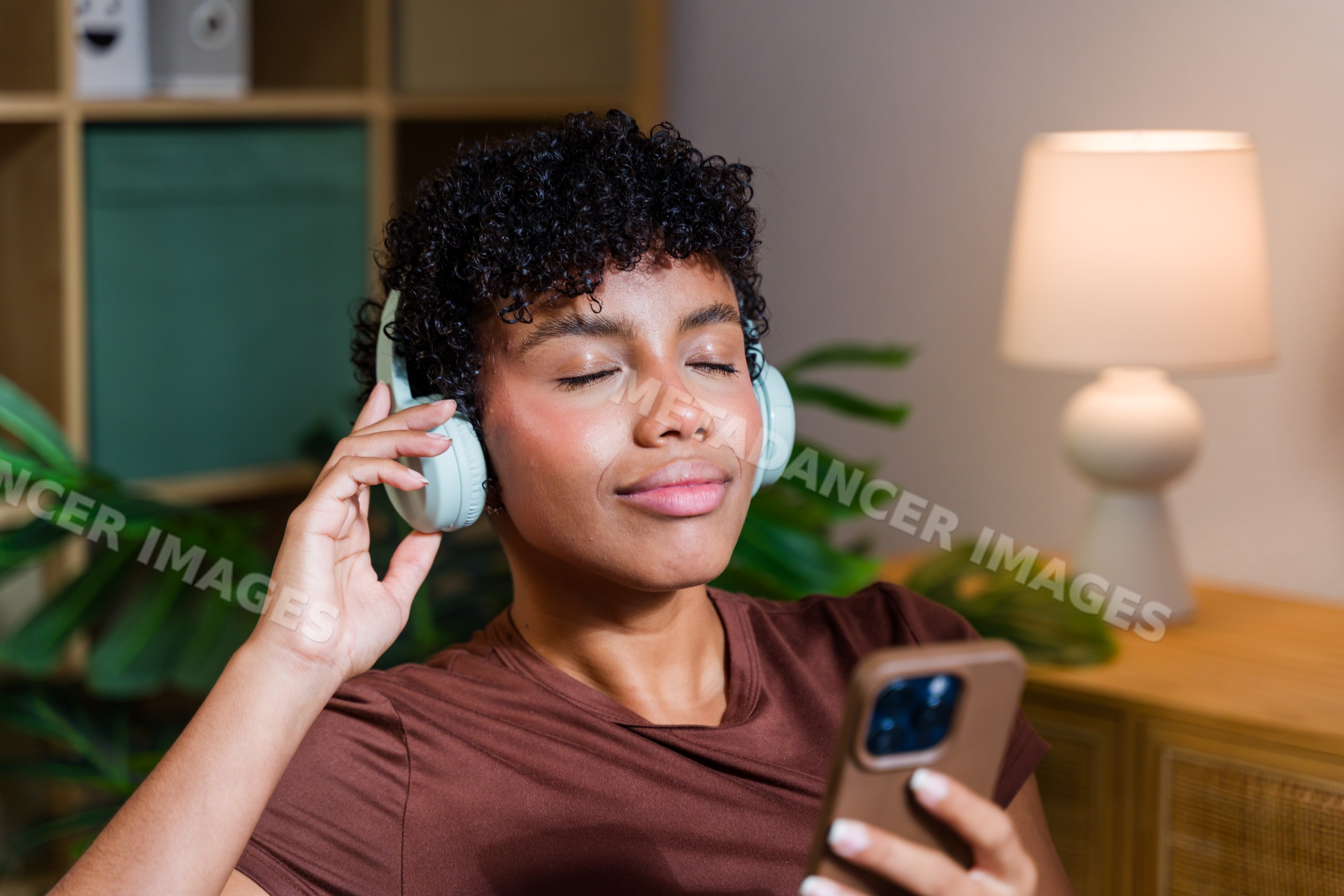 African American woman enjoying music on headphones indoors with phone