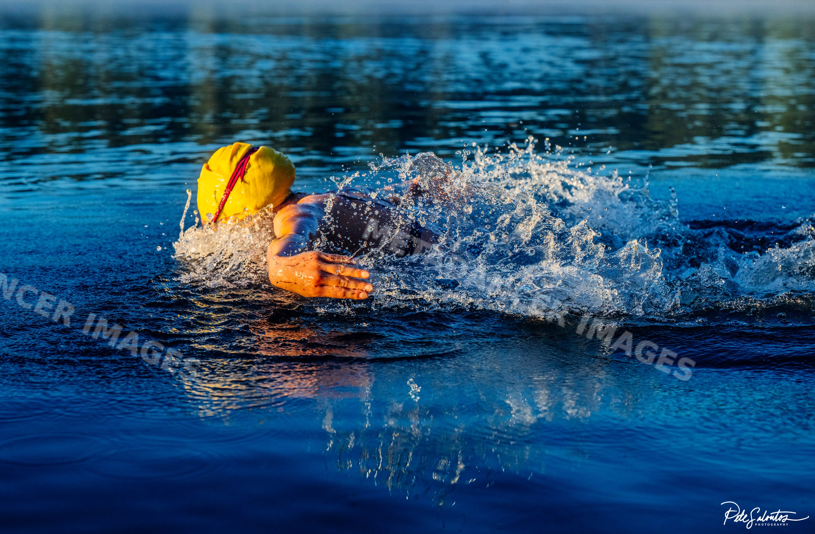 White swimmer in yellow cap performing freestyle stroke in open water