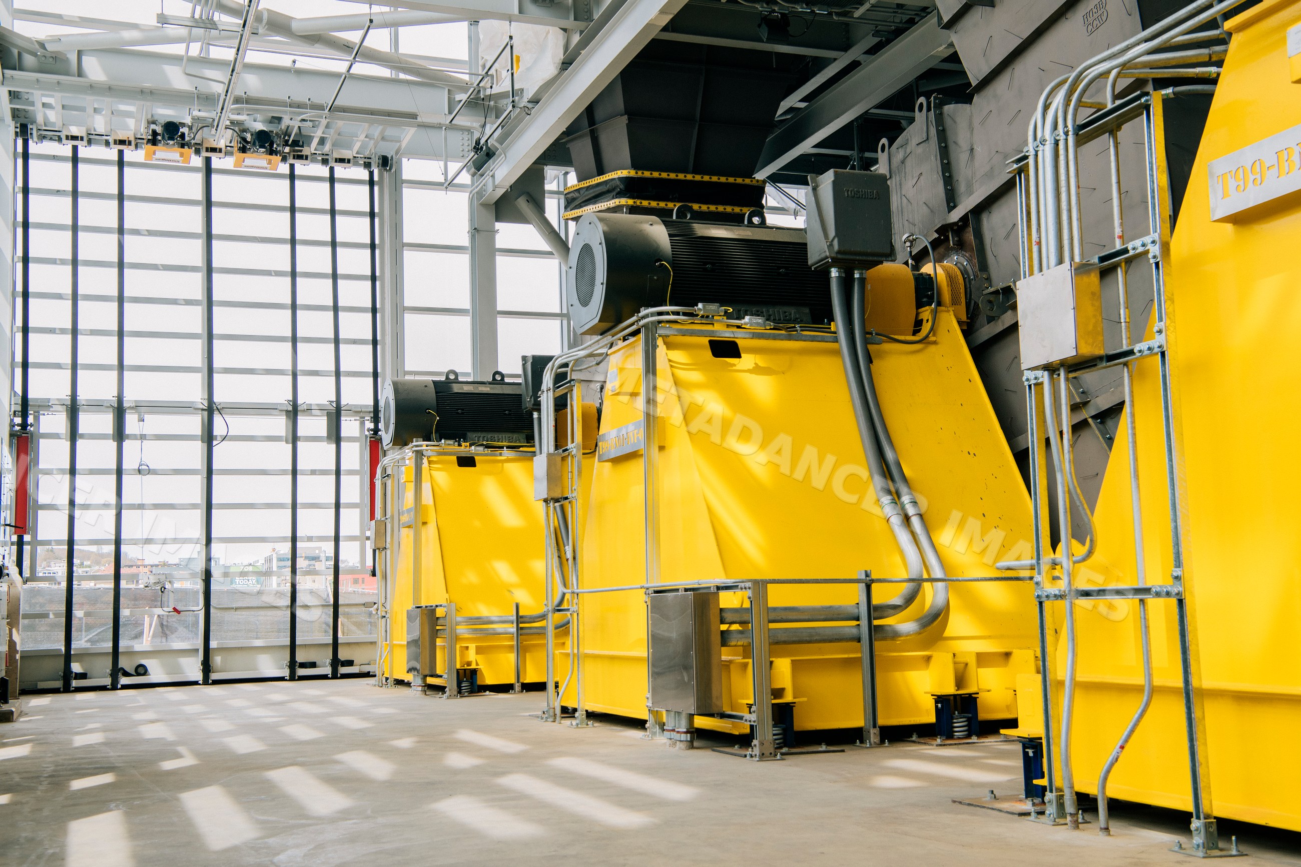 Large yellow industrial machinery seen inside an indoor factory space