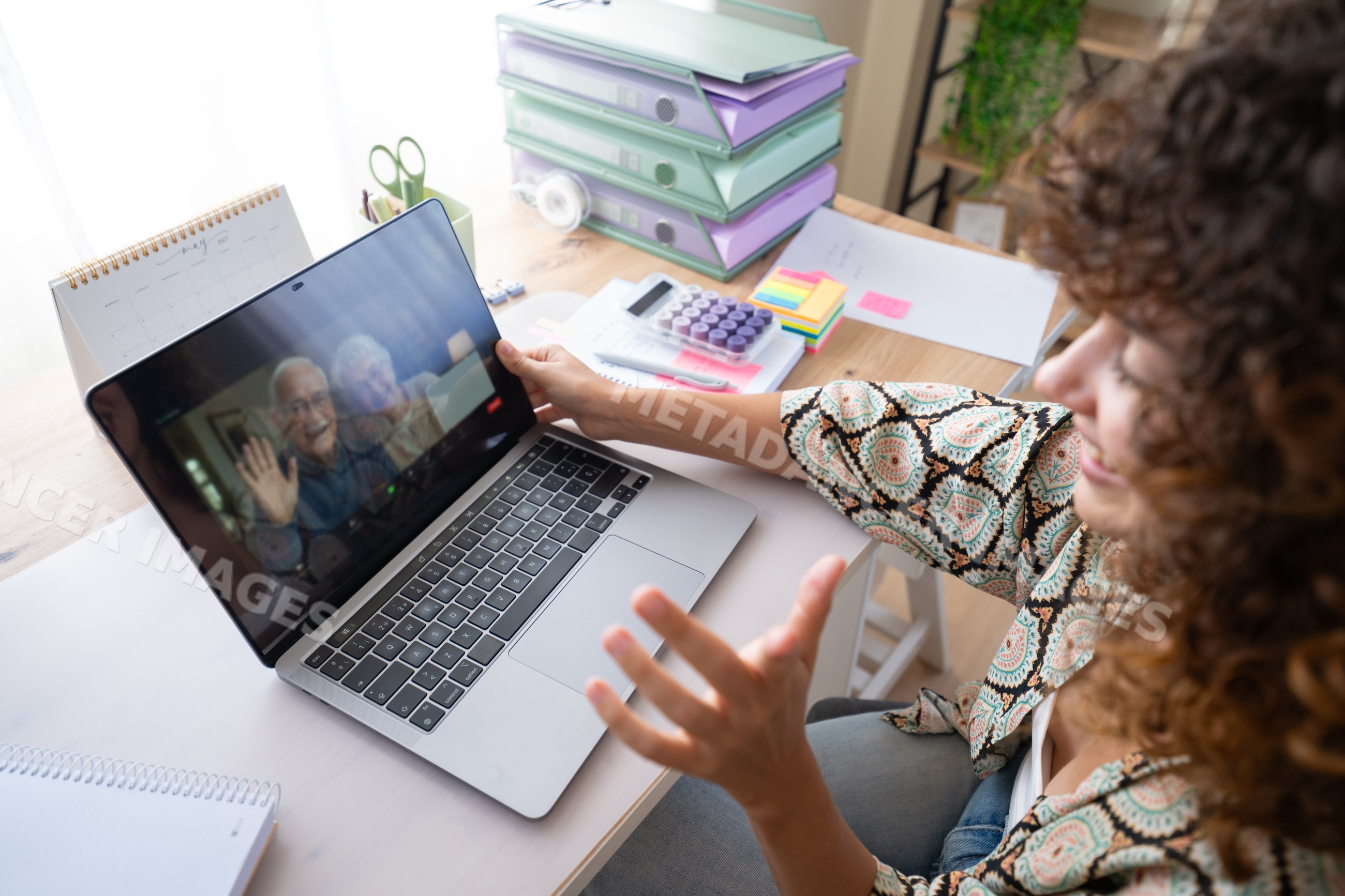 White woman video calling on laptop at home office desk in a office