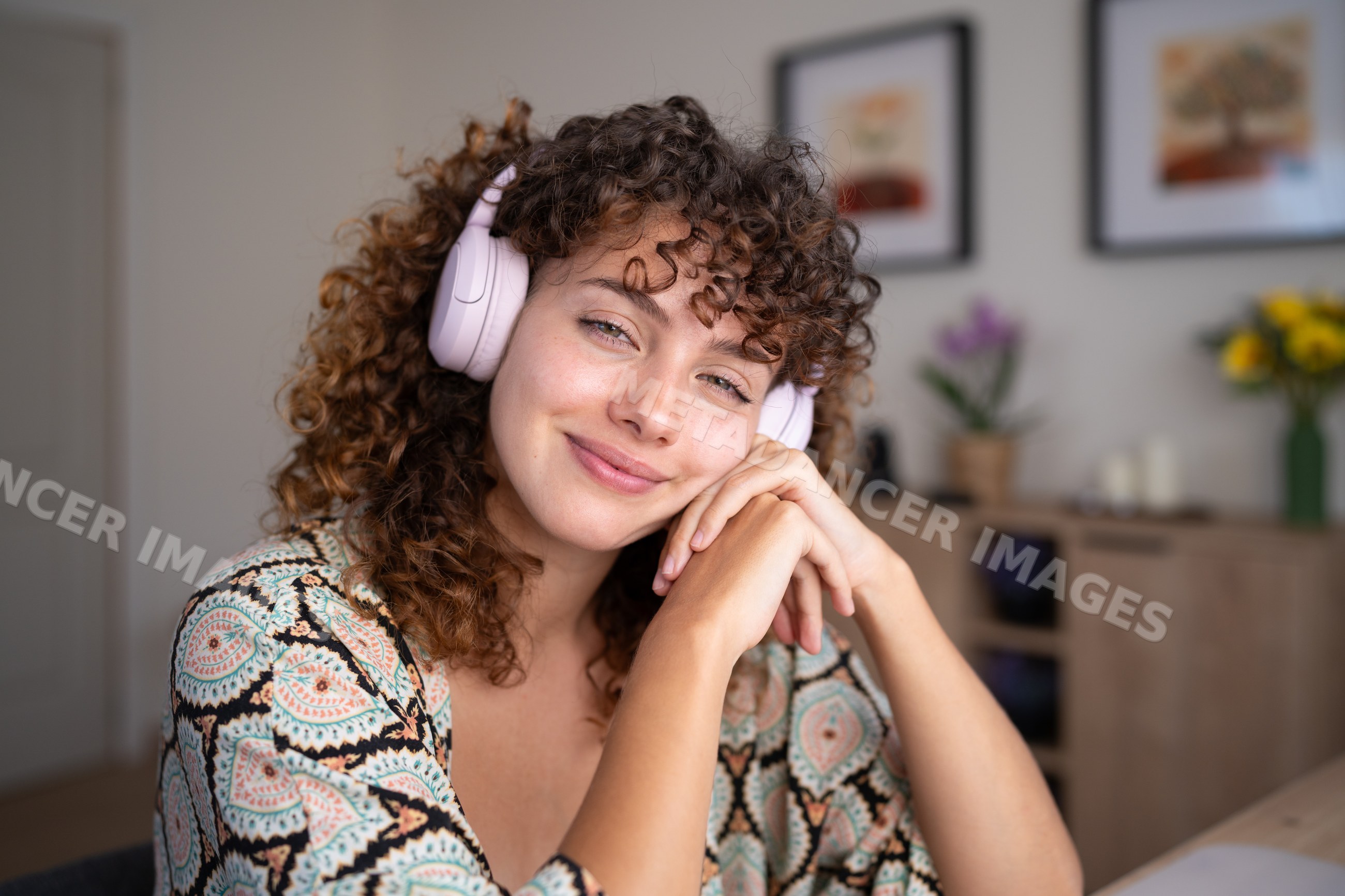 White woman with headphones smiling indoors in a home setting