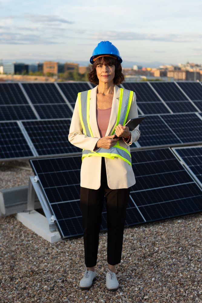 White woman inspecting solar panels wearing construction helmet