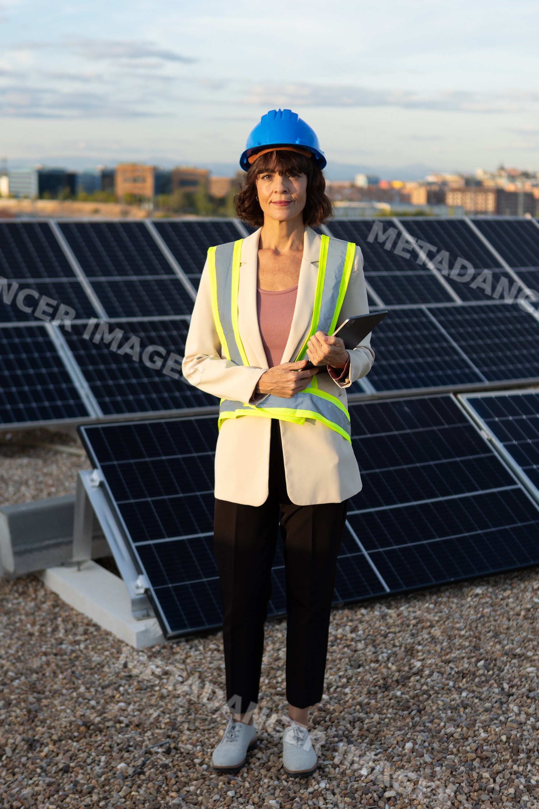 White woman inspecting solar panels wearing construction helmet