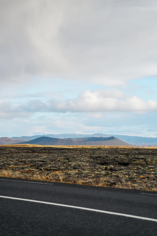 A volcanic crater and lava field landscape near a road in Iceland