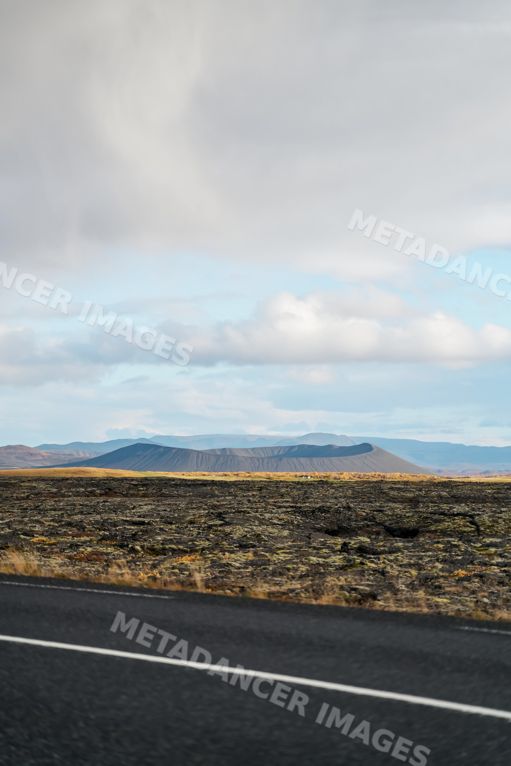 A volcanic crater and lava field landscape near a road in Iceland