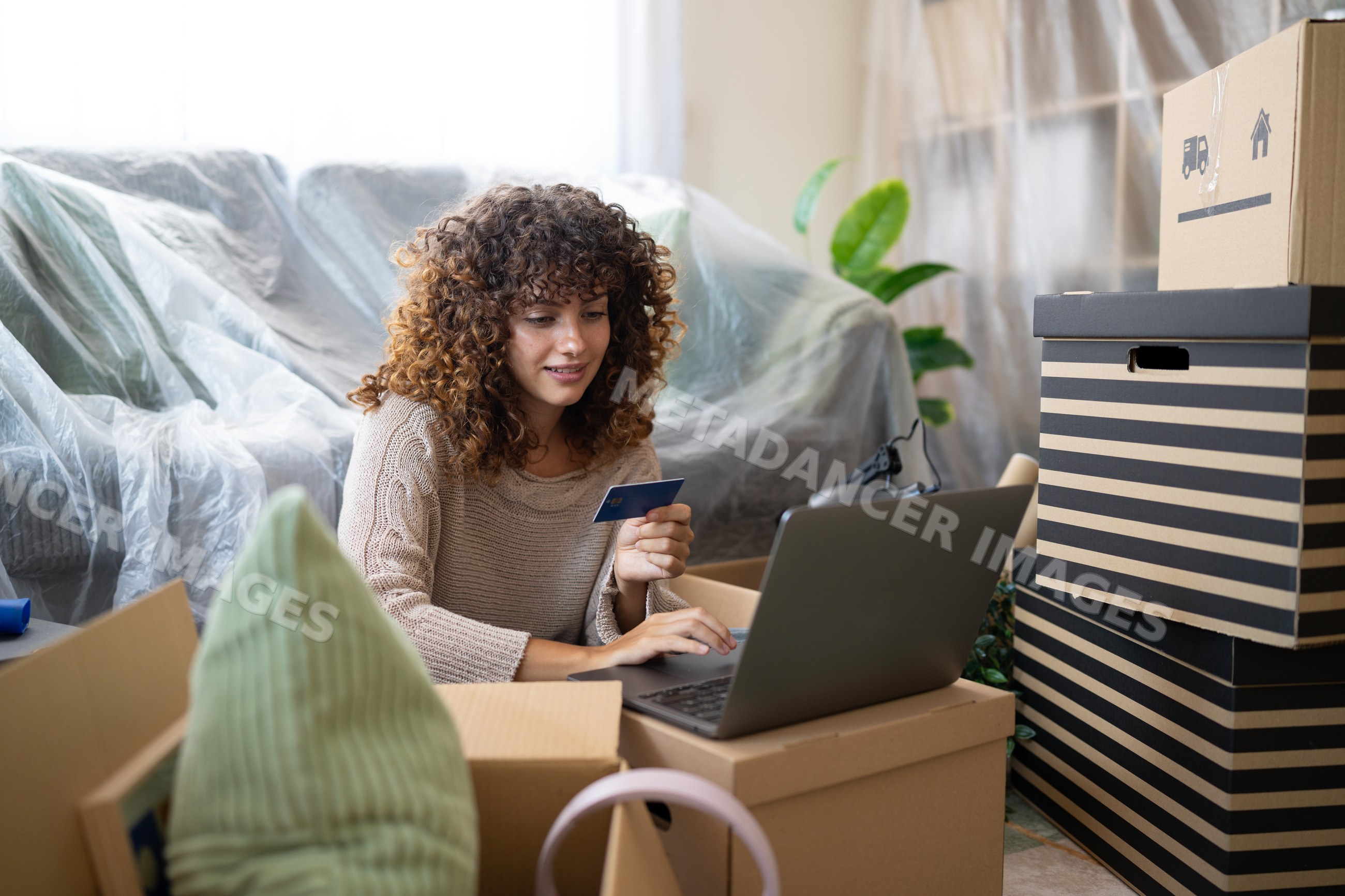 White woman shopping online using credit card during home move