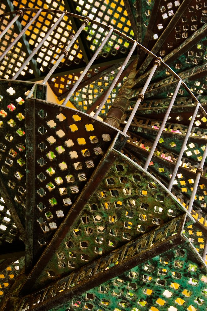 Spiral metal staircase with decorative patterns viewed from below