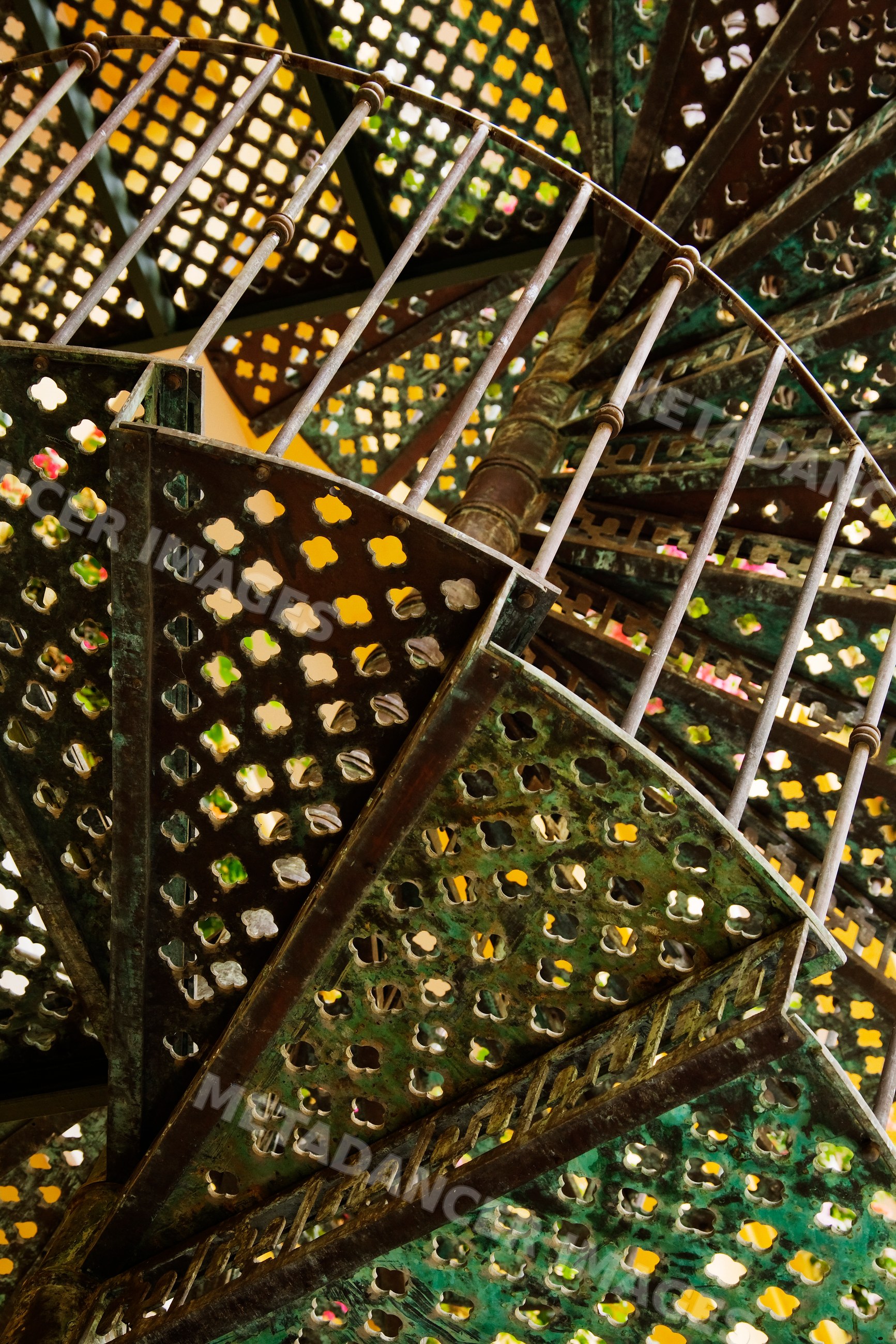 Spiral metal staircase with decorative patterns viewed from below