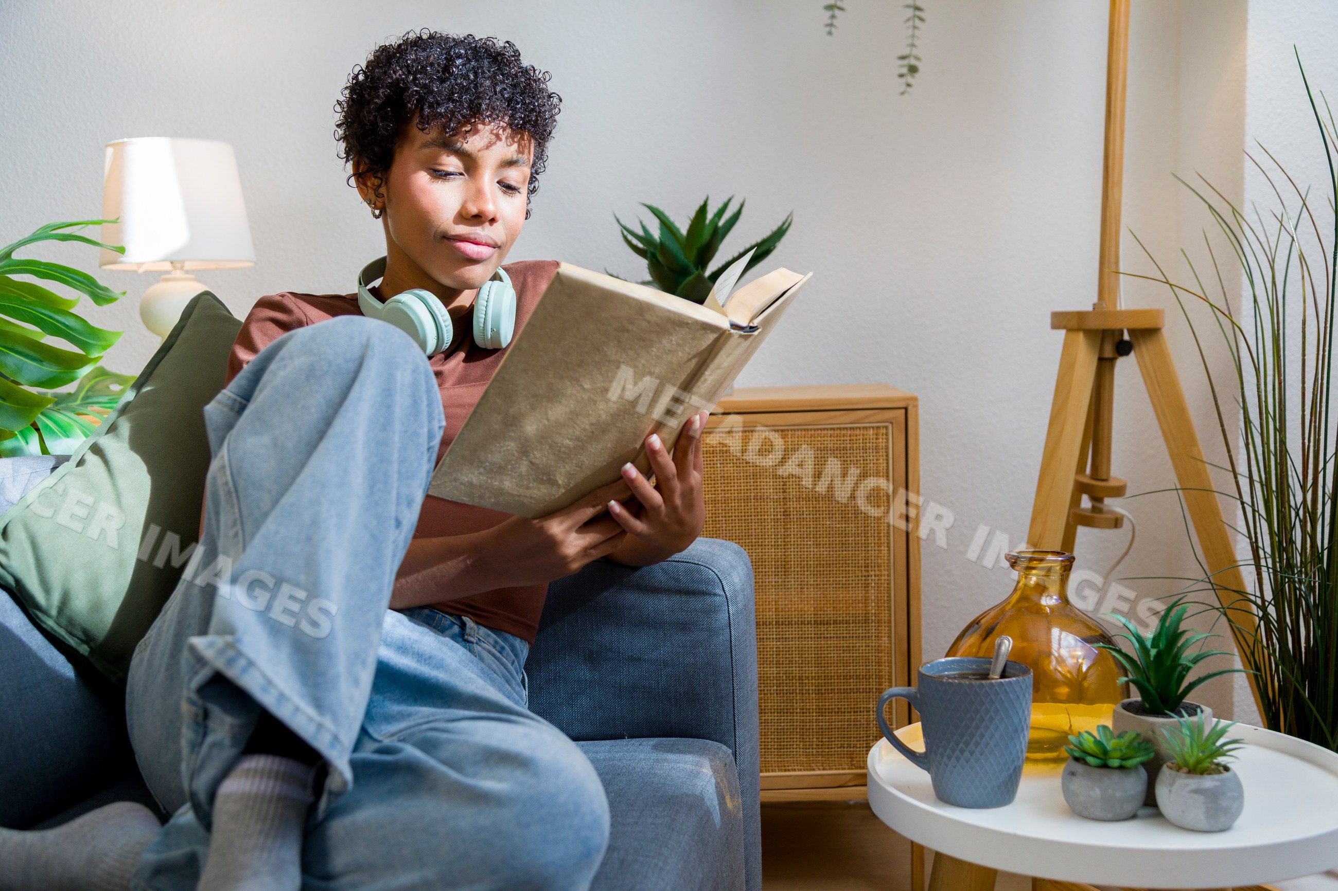African American woman reading book with headphones and coffee