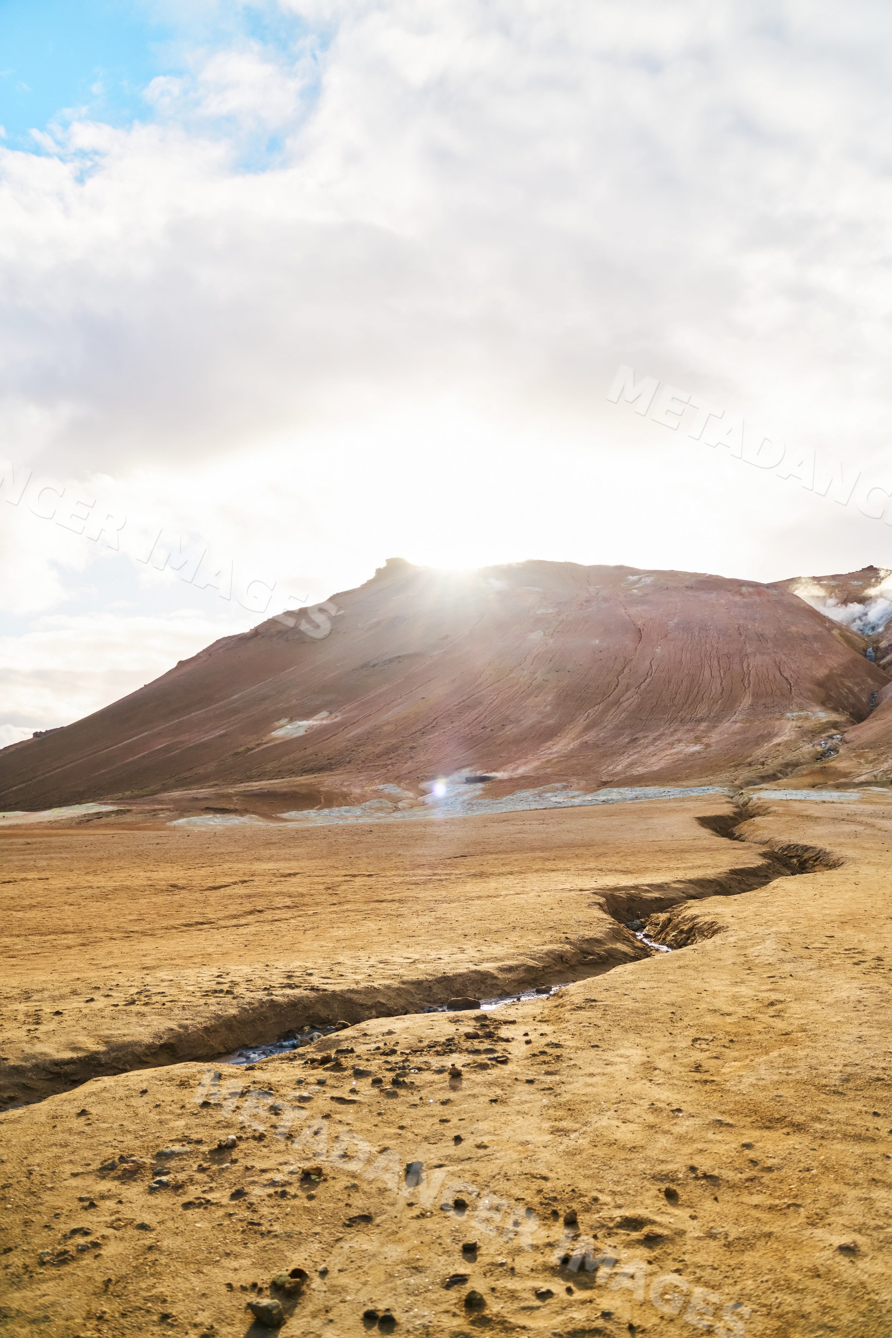 Sunlight illuminates a cracked volcanic landscape with geothermal