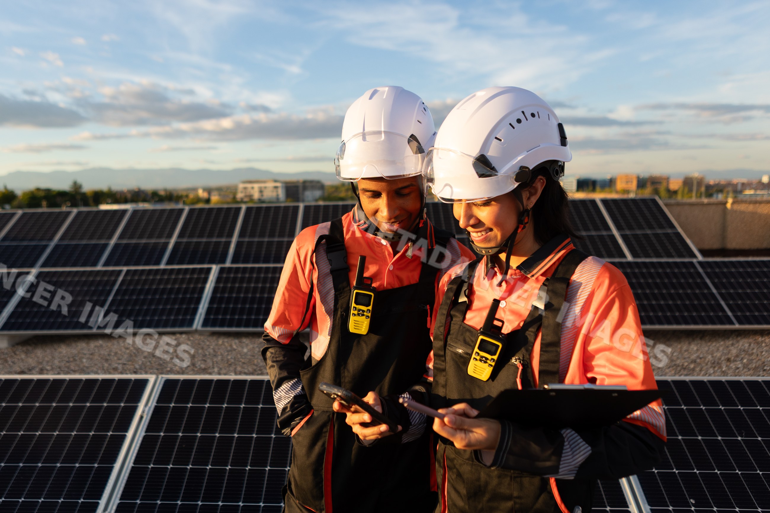 Hispanic workers inspecting solar panels outdoors at sunset in Madrid